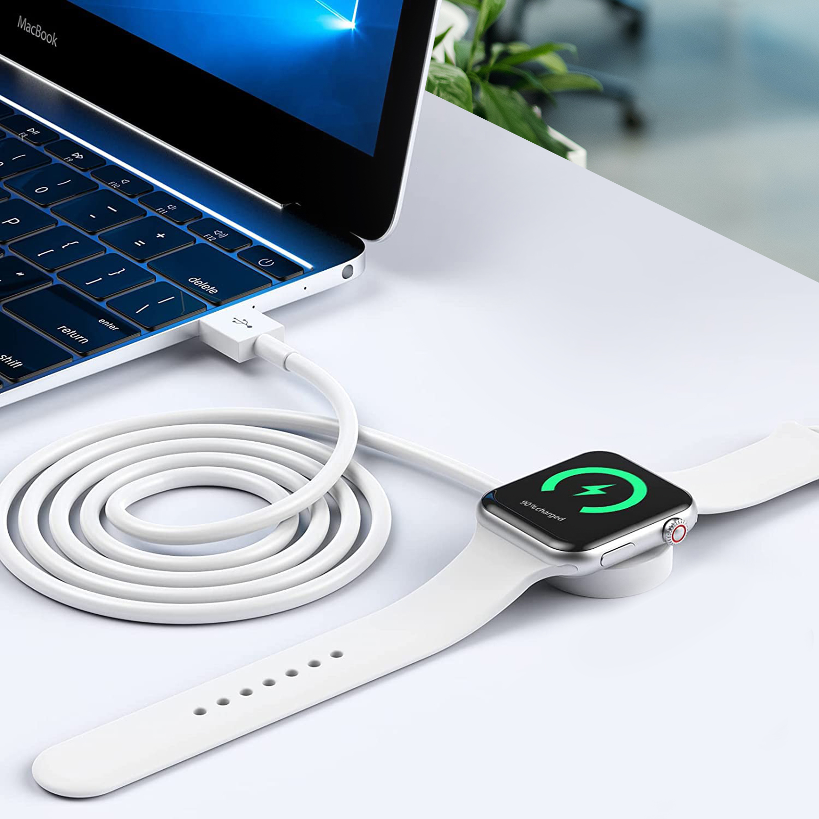 Ein weißes Ladekabel ist mit einem Laptop und einer Smartwatch auf einer weißen Oberfläche verbunden und zeigt das Aufladen an.
