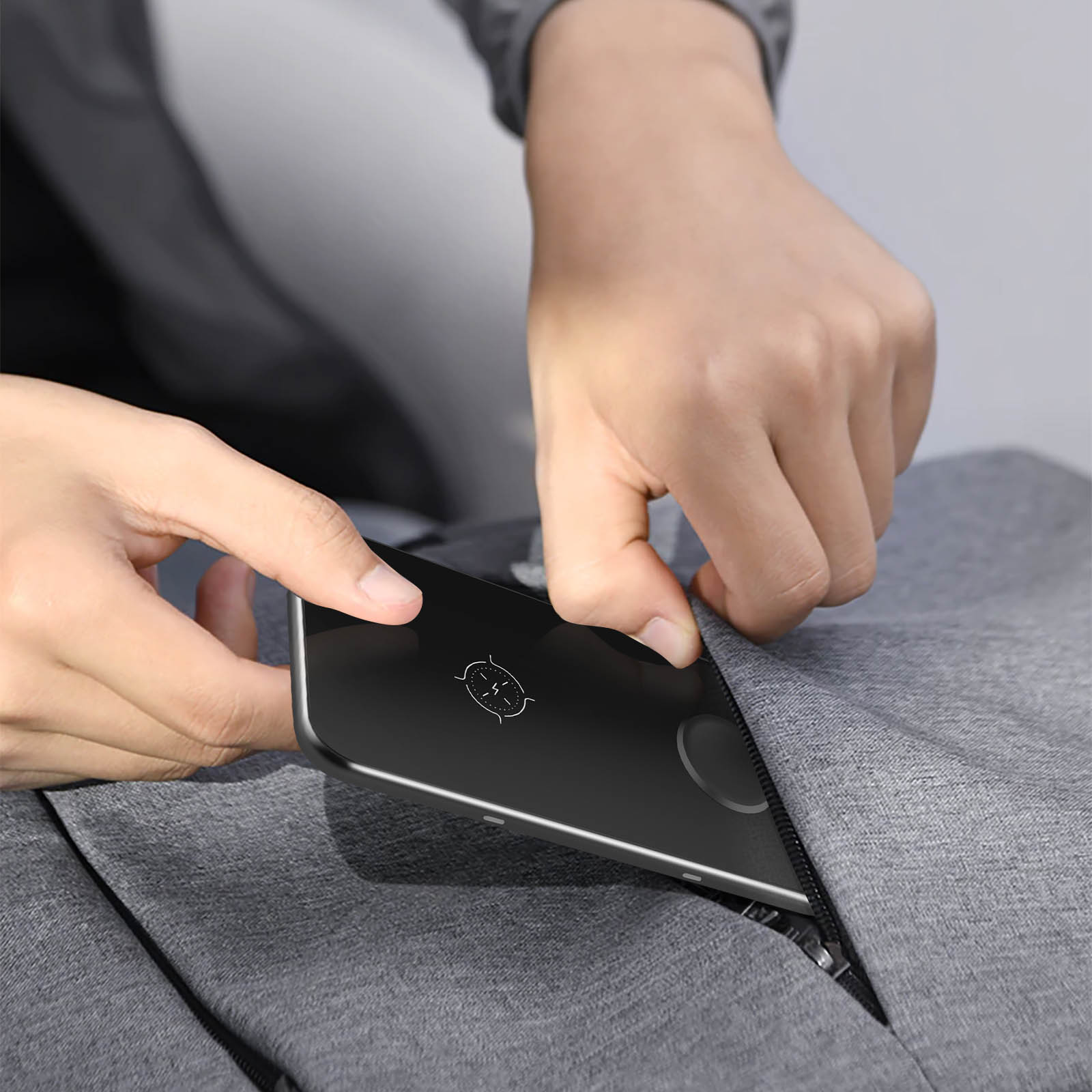 Une personne mettant un téléphone noir dans une poche. Le téléphone a un logo.