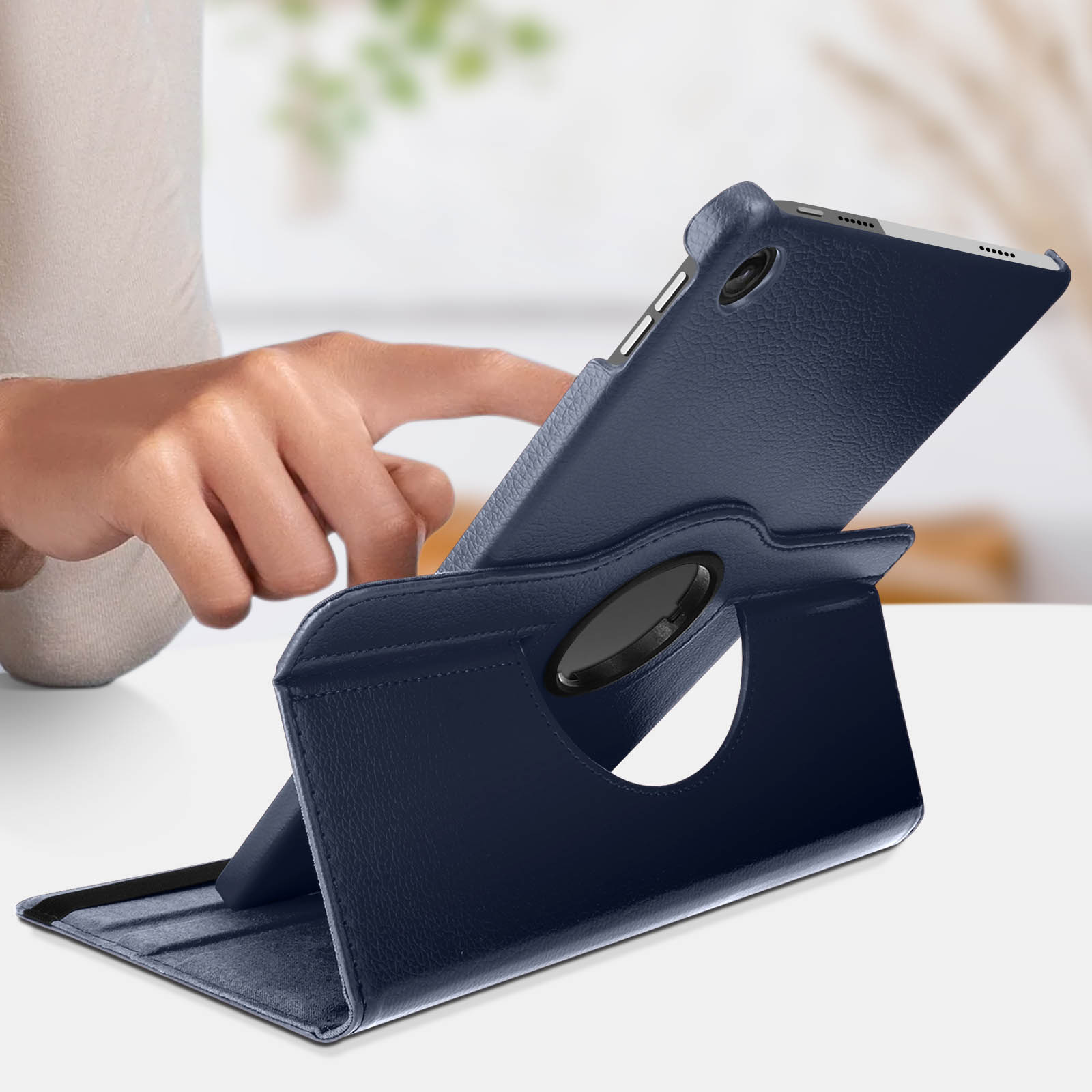 Tablet in una custodia di pelle blu, tenuto in mano. Sfondo bianco.