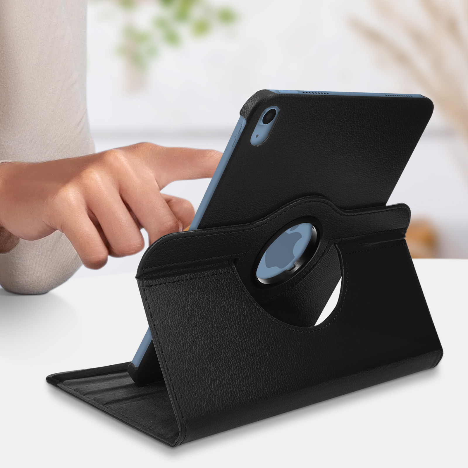 Tablet nero in custodia di pelle nera. Mano visibile. Su superficie bianca.