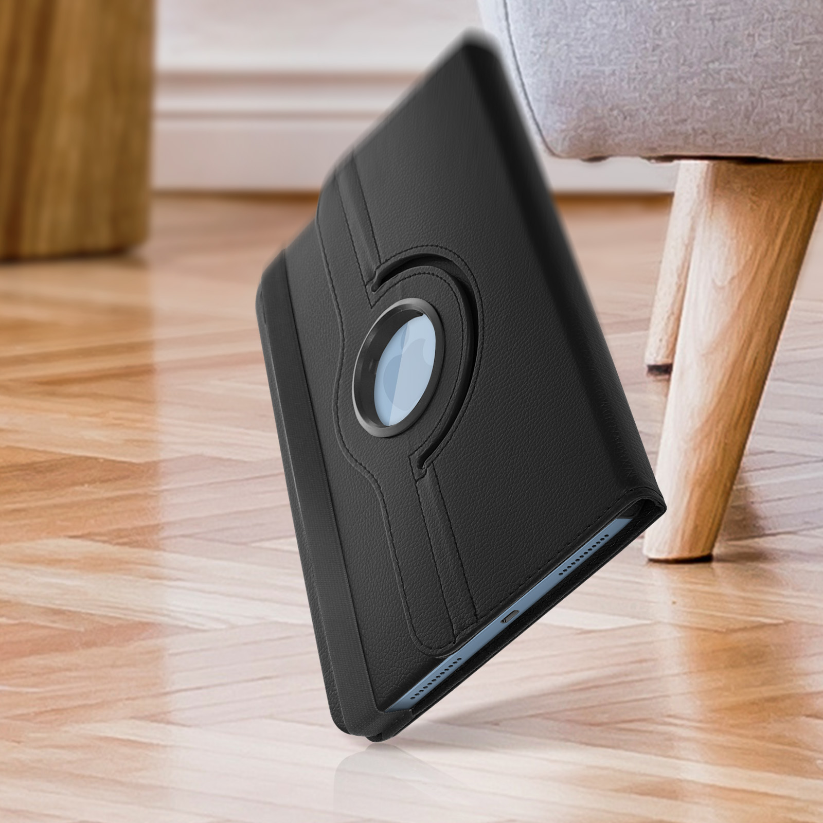 Custodia per tablet in pelle nera con supporto rotante. Poggia su una superficie in legno.