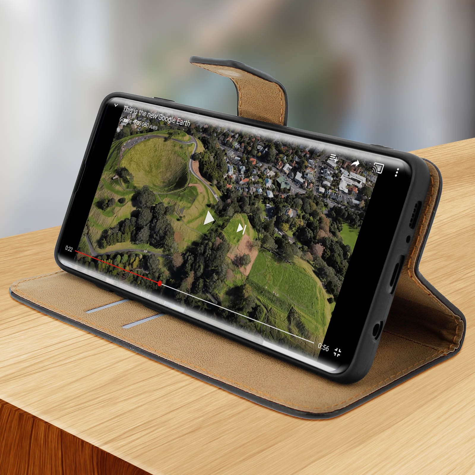 Smartphone in custodia che mostra un video. Sfondo: tavolo di legno.