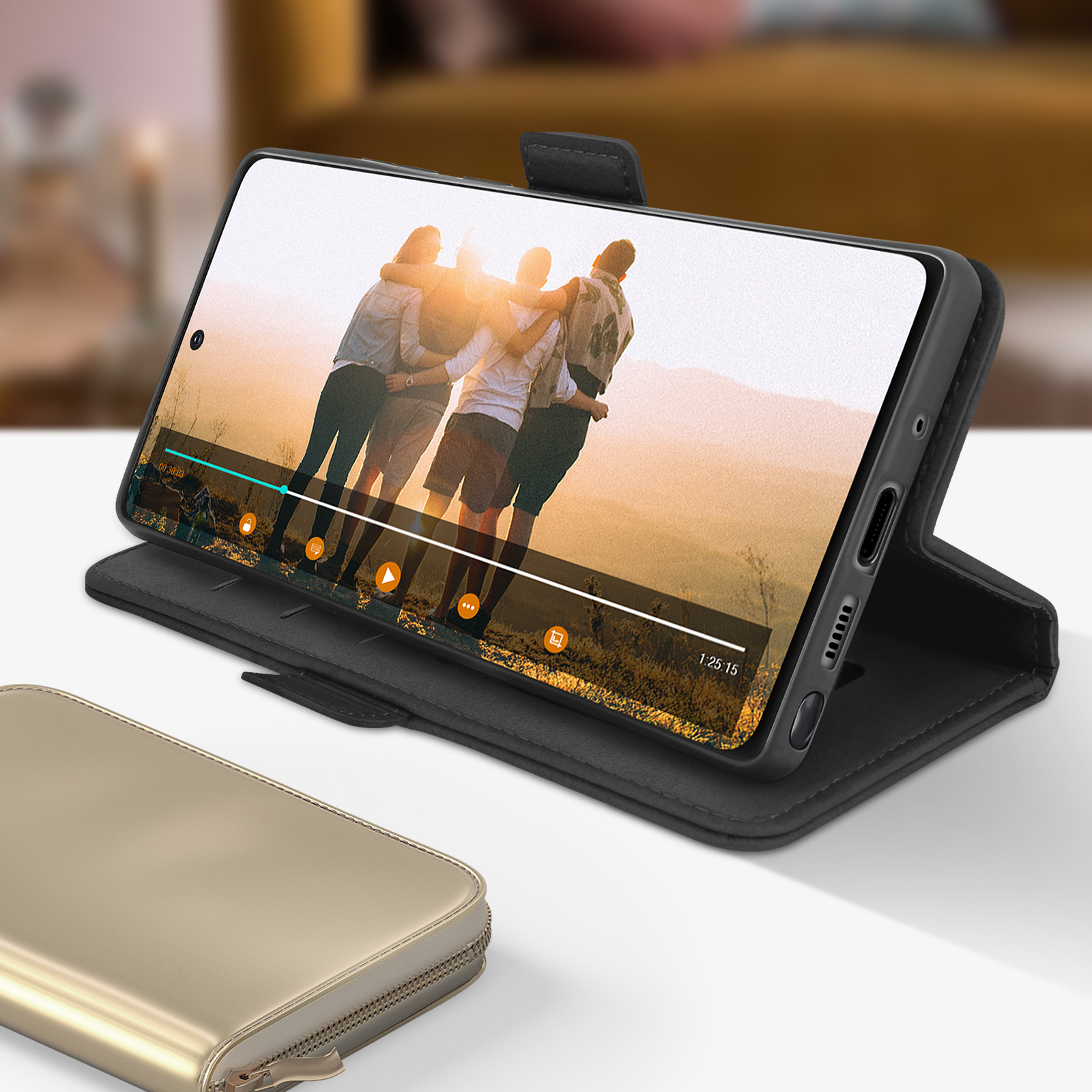 Smartphone in custodia nera con video sullo schermo. Portafoglio dorato in primo piano.