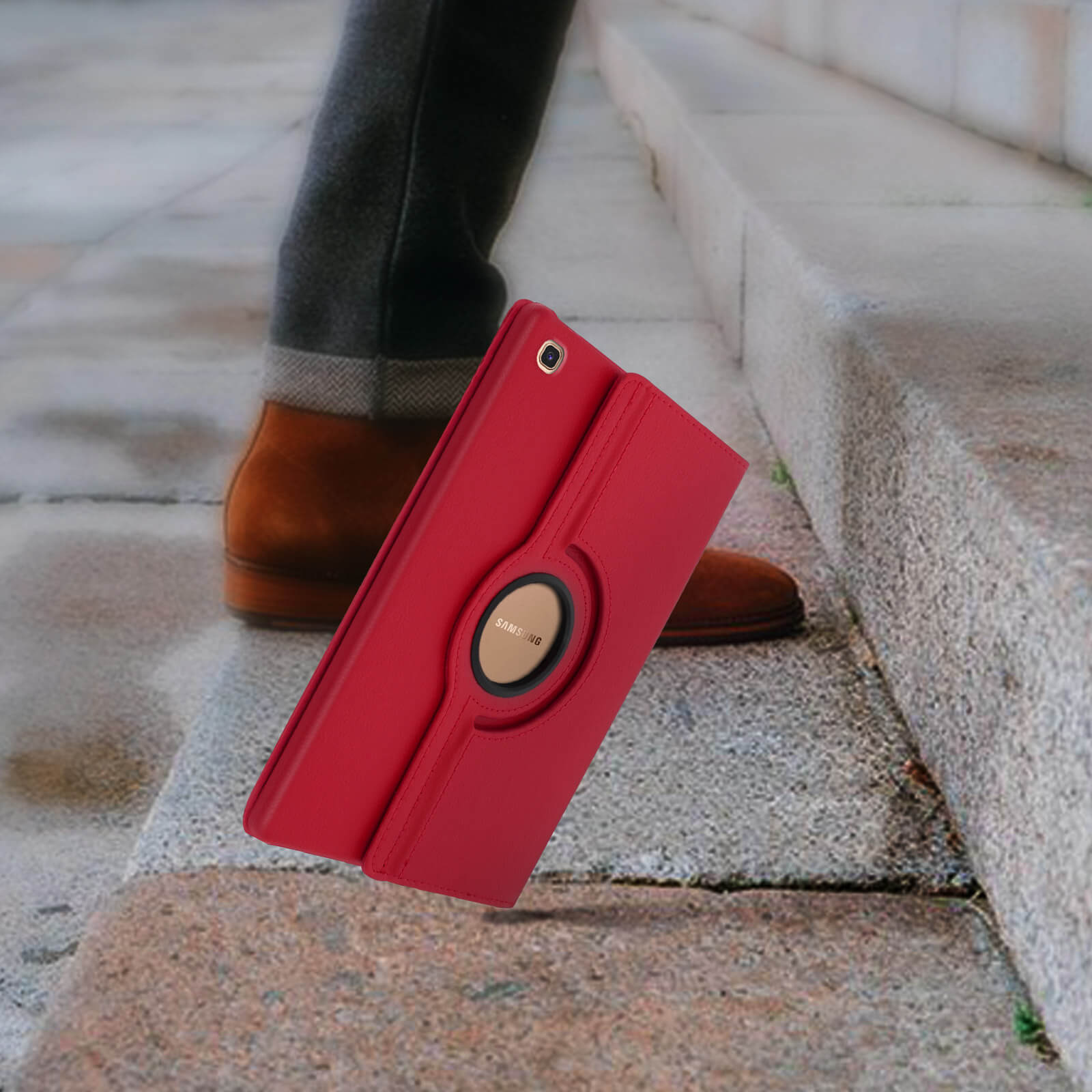 Custodia per tablet rossa con supporto, che cade su gradini. Gamba e scarpa di un uomo sullo sfondo.