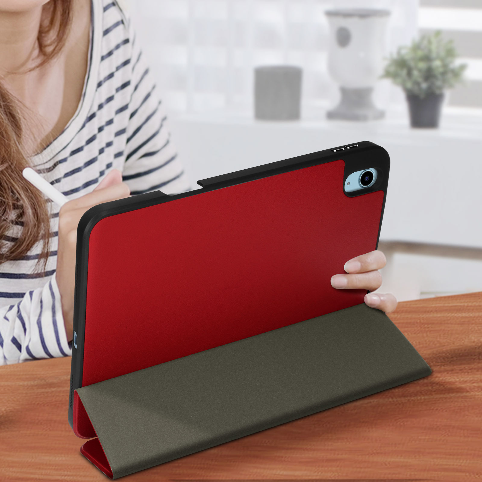 Tablet in custodia rossa, su tavolo di legno. Donna che tiene una penna. Supporto verde oliva.