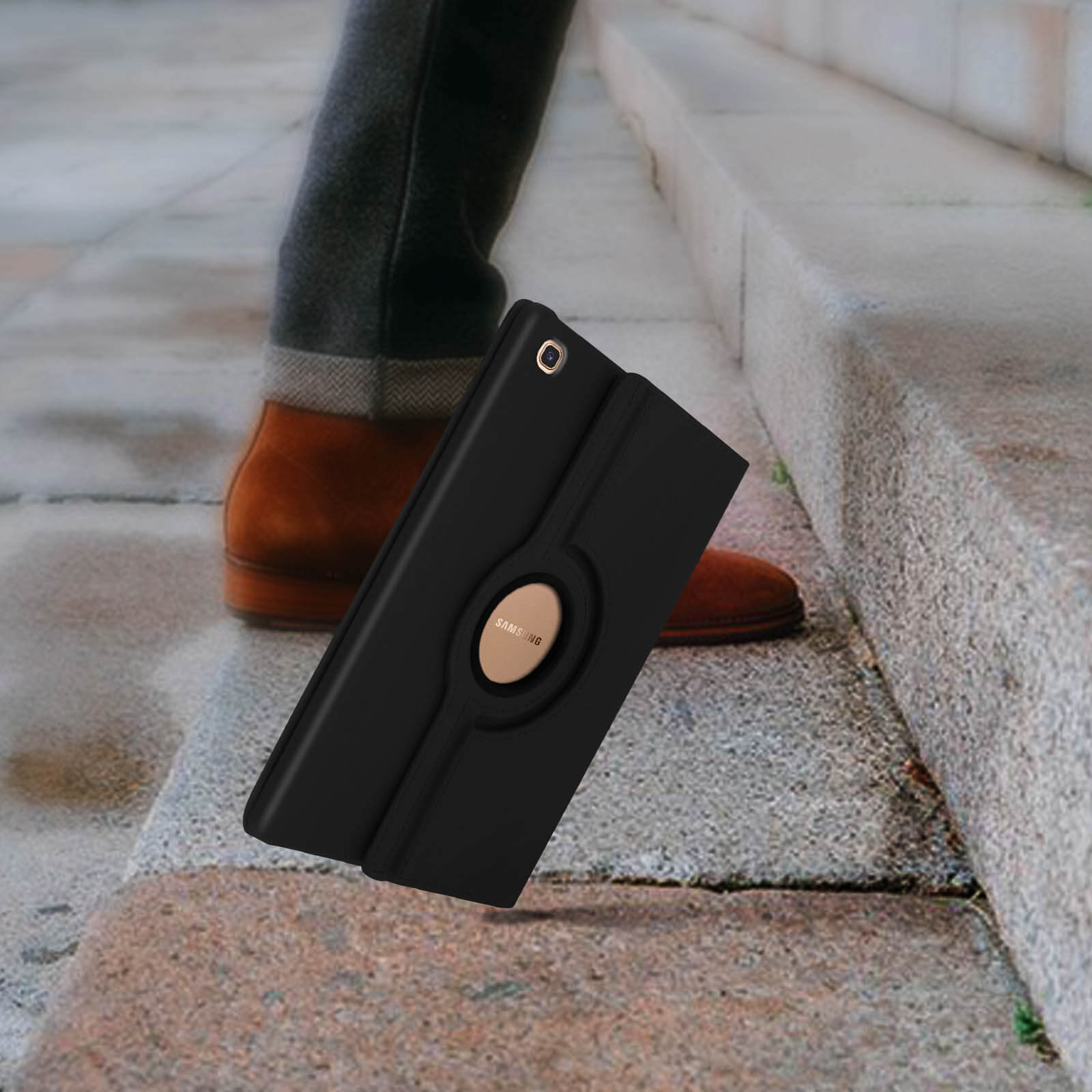 Custodia per tablet nera su gradini, con gambe e scarpe marroni di una persona.