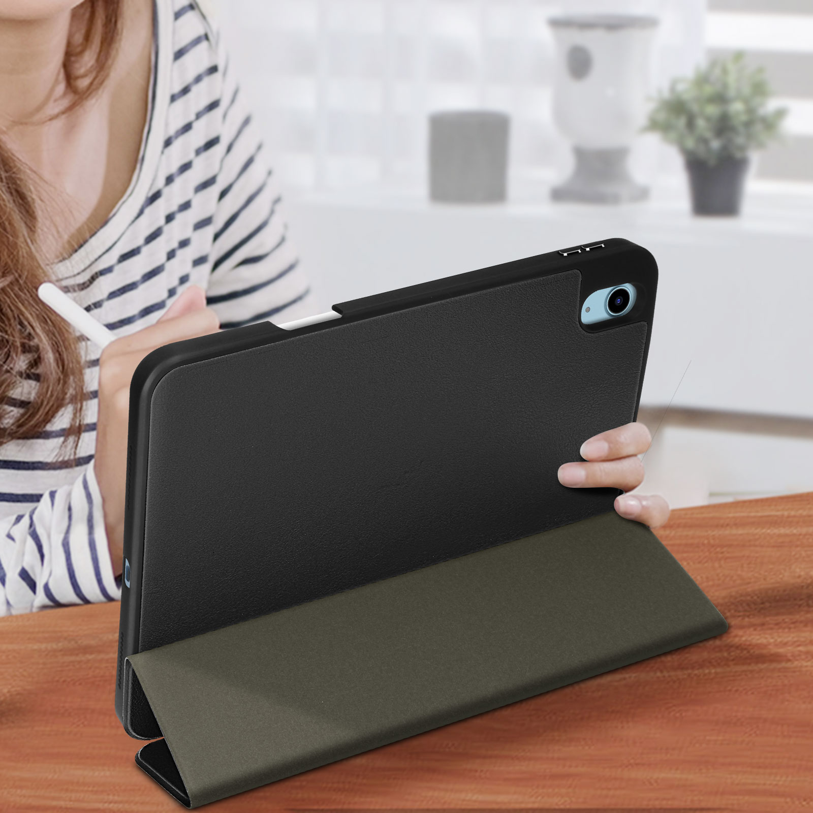 Tablet in custodia nera con supporto su tavolo di legno, tenuto da una persona.