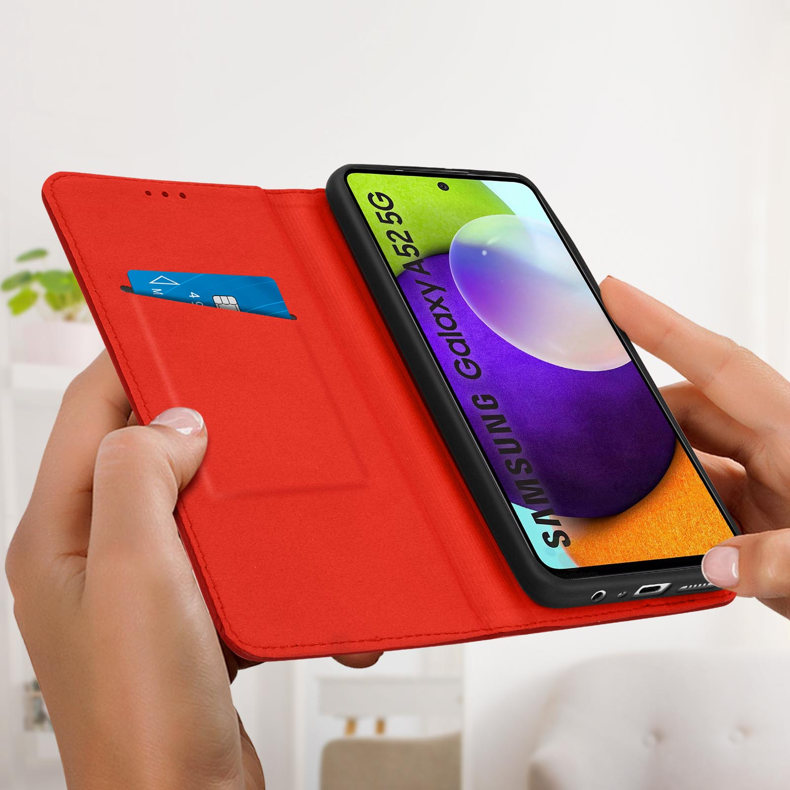 Custodia rossa per telefono, aperta. Mano che la tiene, Samsung e carta di credito.