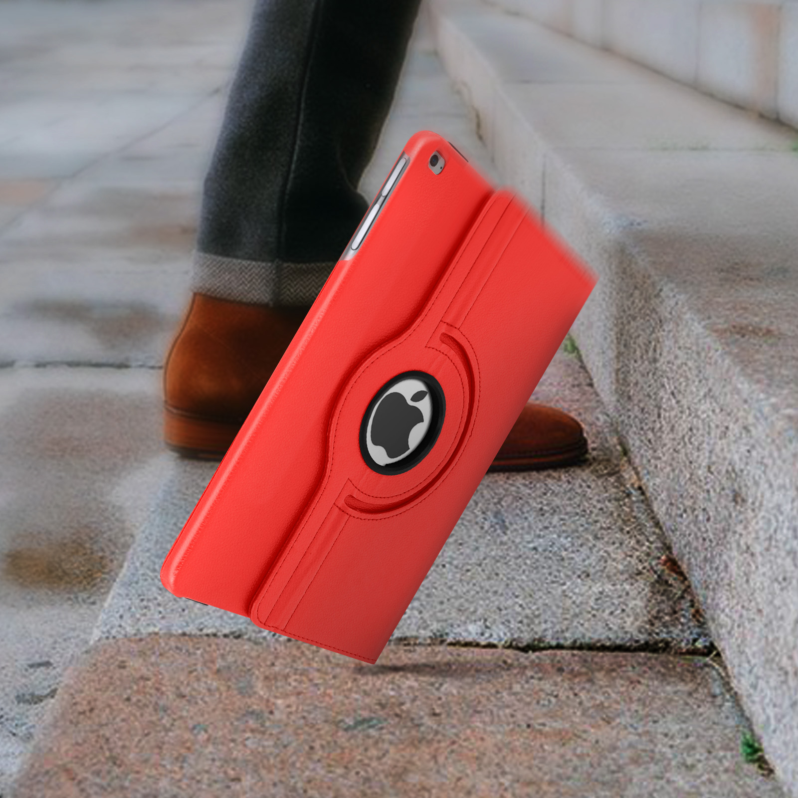 Custodia rossa per tablet con logo Apple nero, tenuta in diagonale da un piede e una gamba su superficie in pietra.