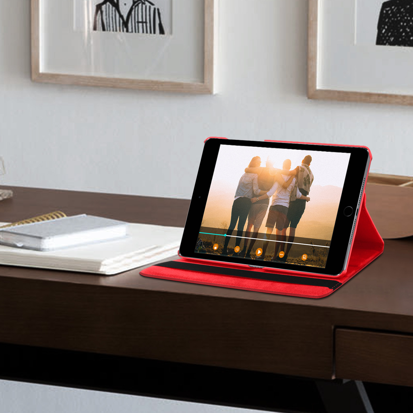Tablet rosso in custodia rossa su una scrivania di legno. Lo schermo mostra un video di persone.