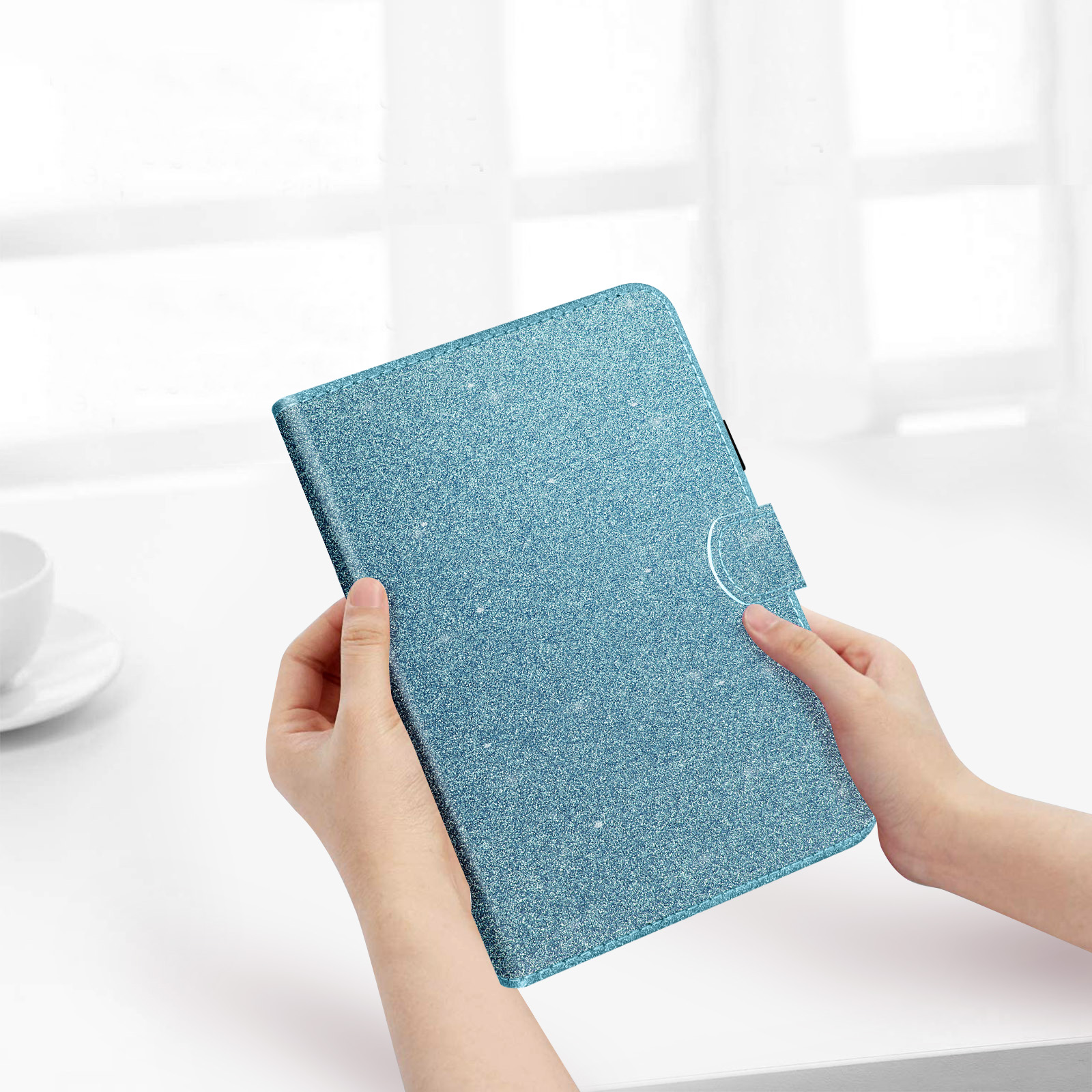 Una custodia per tablet blu glitterata. Una persona tiene la custodia con entrambe le mani.