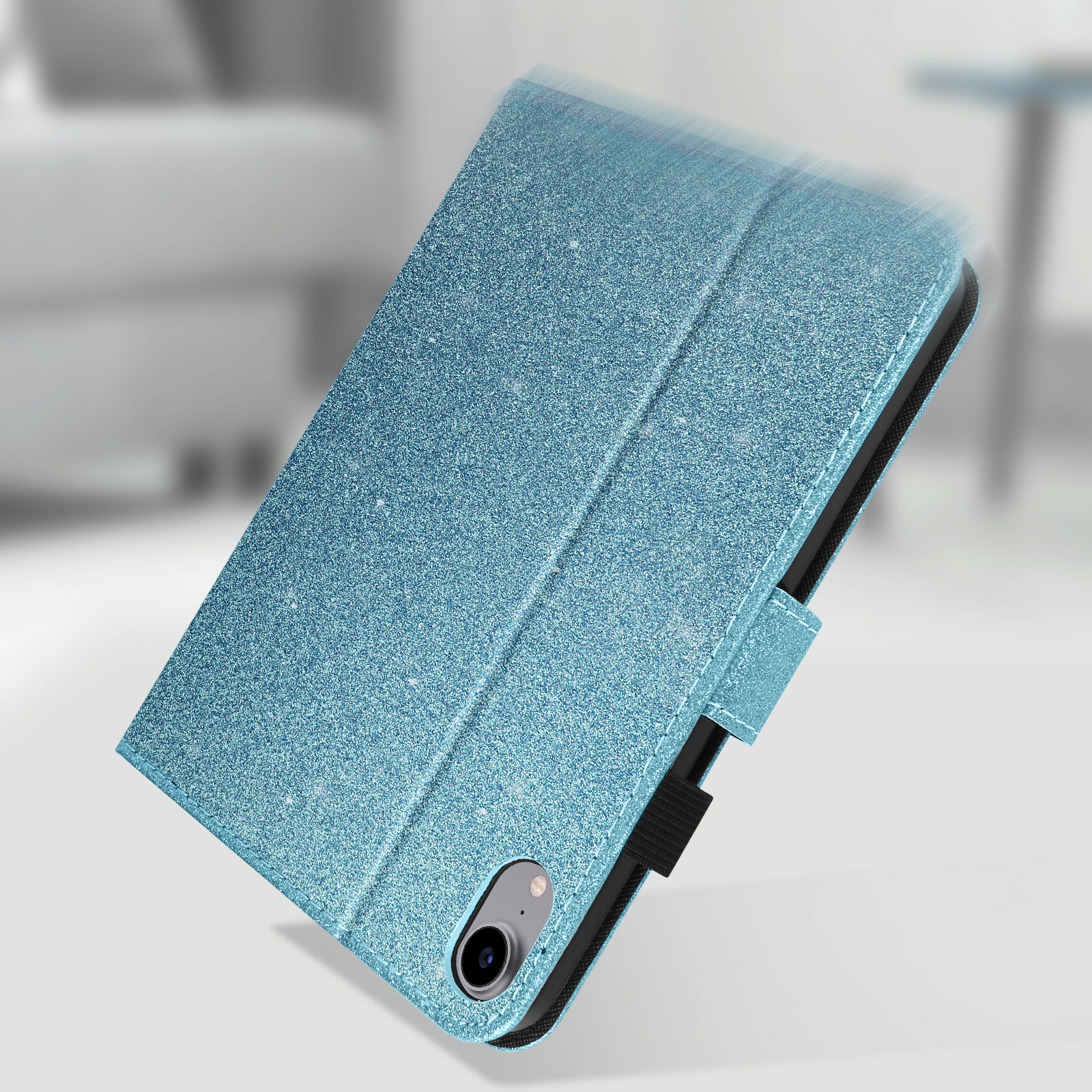 Custodia per tablet blu glitterata, chiusa, con una leggera angolazione, su sfondo sfocato.