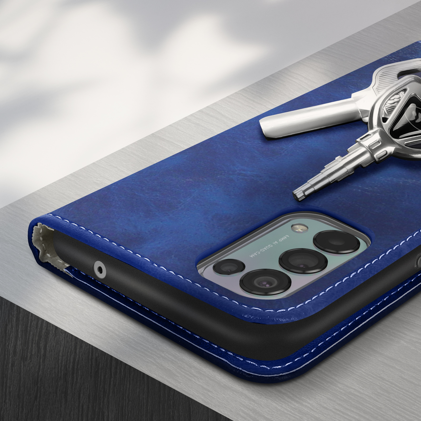 Étui de téléphone bleu avec une clé argentée posée dessus. L'étui a une découpe pour l'appareil photo et une surface texturée.