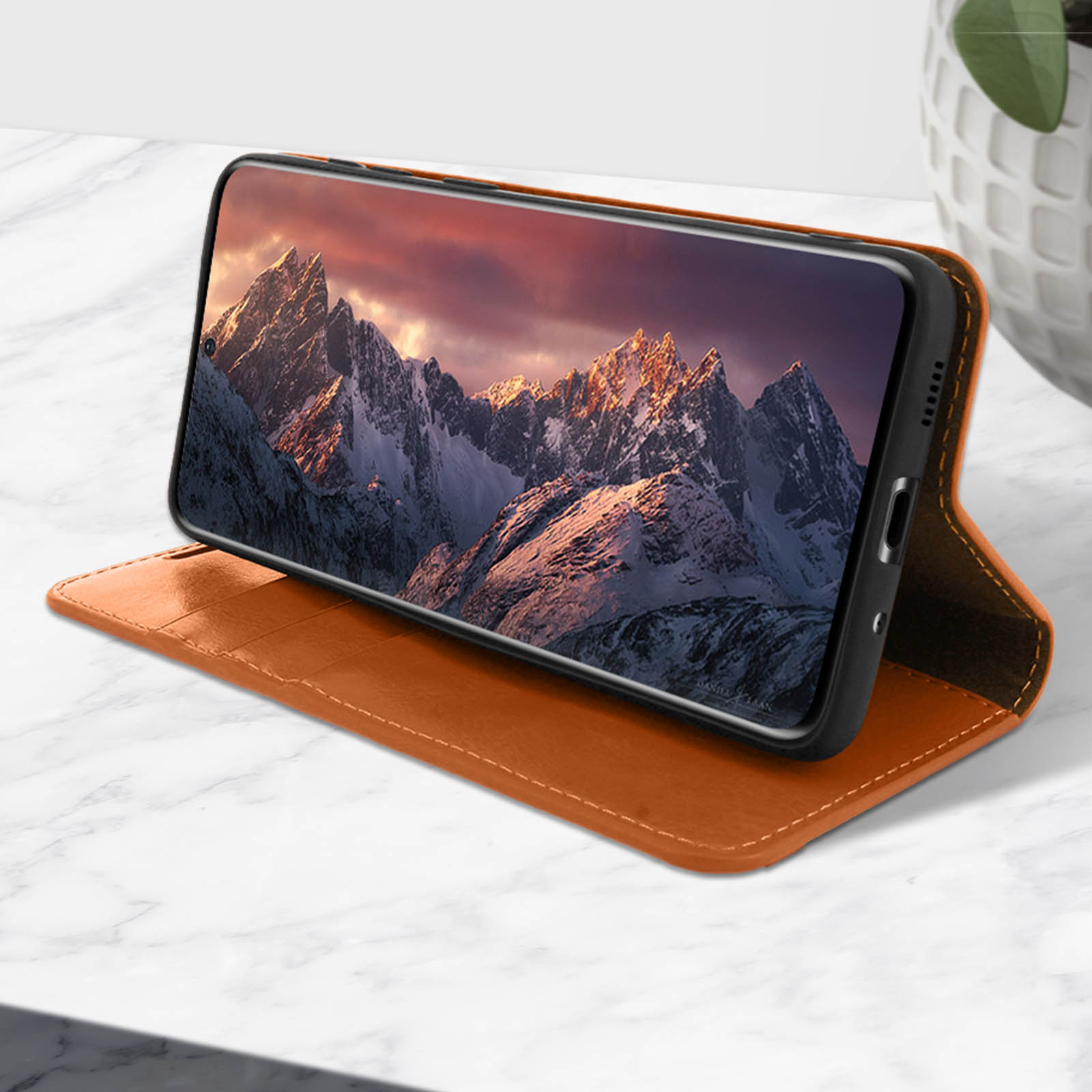 Open bruine telefoonhoes met een smartphone met een berglandschap.
