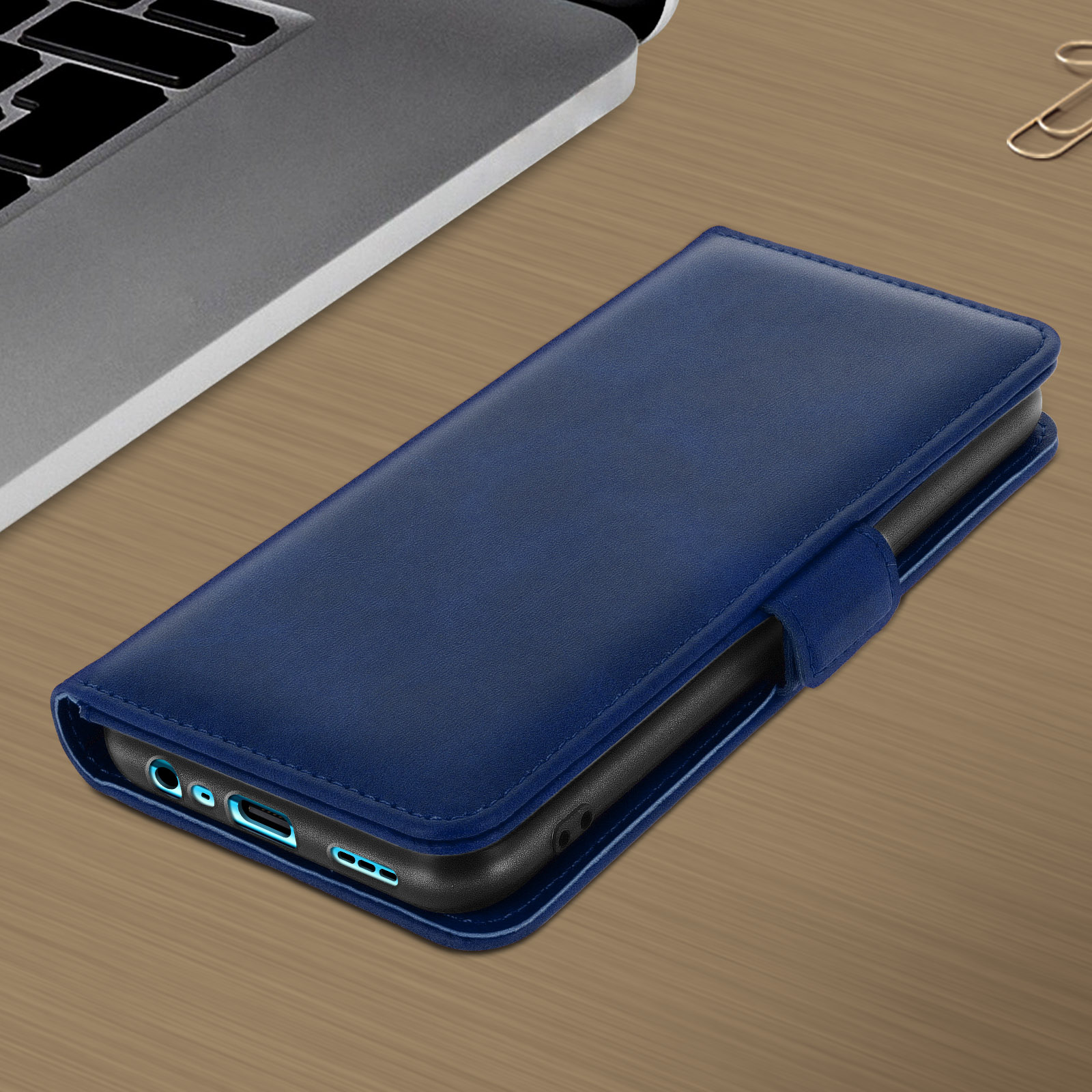 Un étui de téléphone bleu avec un téléphone à l'intérieur, posé sur une table en bois à côté d'un ordinateur portable.
