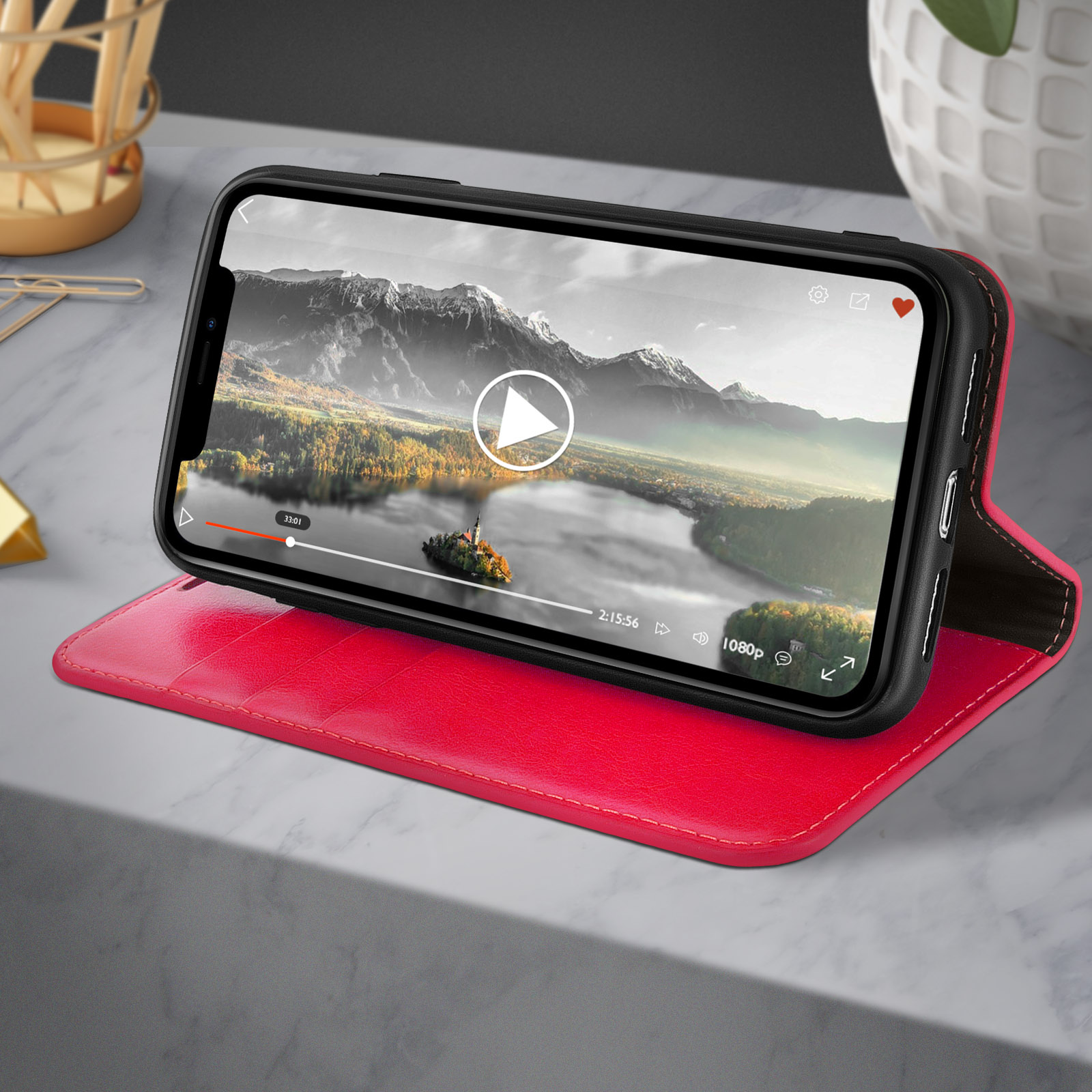 Telefono in custodia di pelle rossa, video sullo schermo. Superficie marmorea.