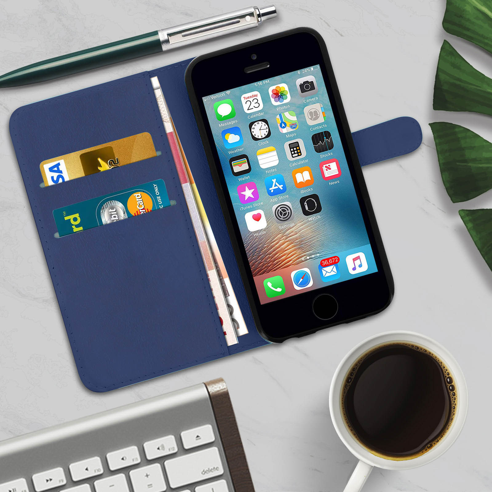 Un telefono in una custodia blu con carte e denaro. Tazza di caffè e tastiera sul tavolo.