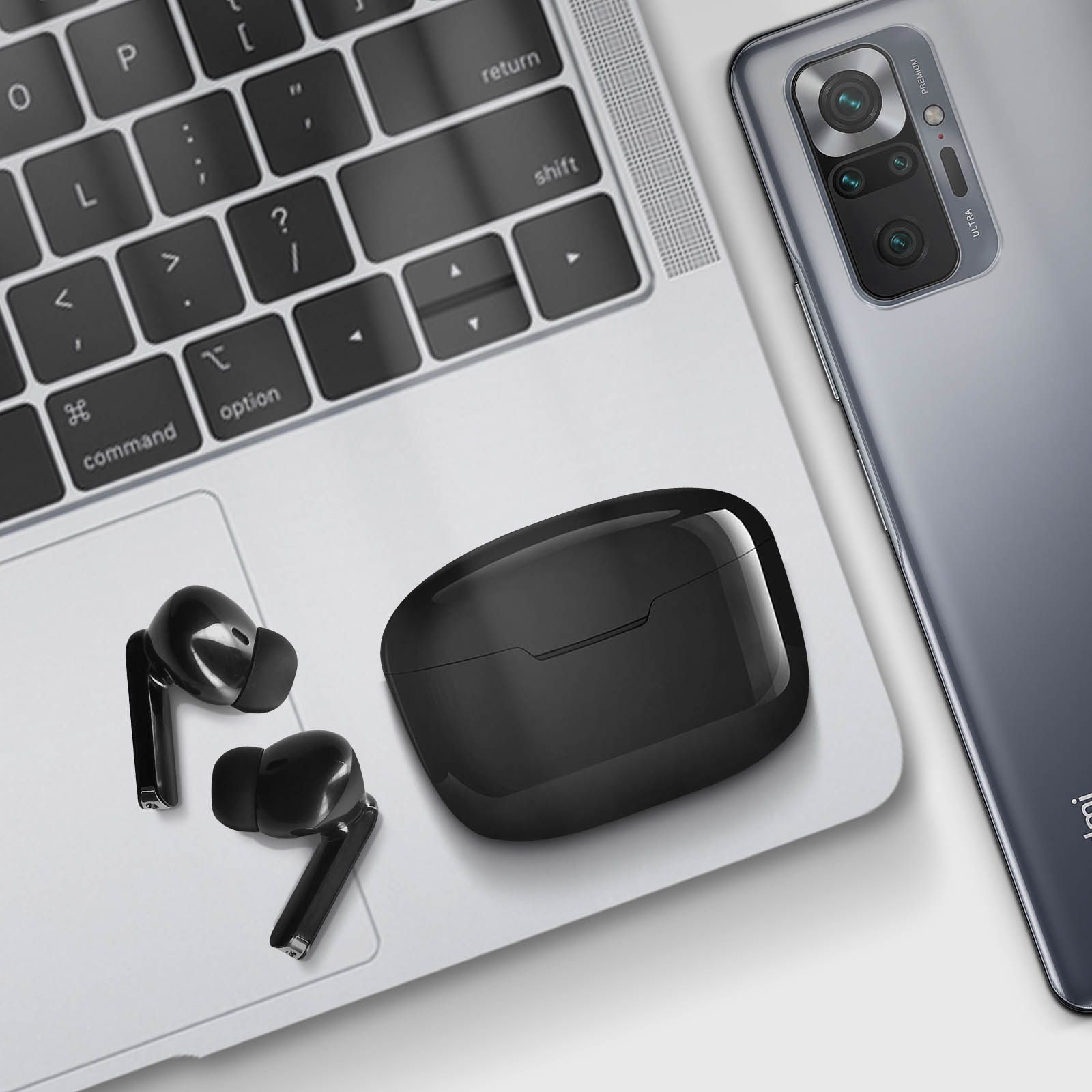 Ordinateur portable, écouteurs et étui de chargement, et un smartphone sur une table.