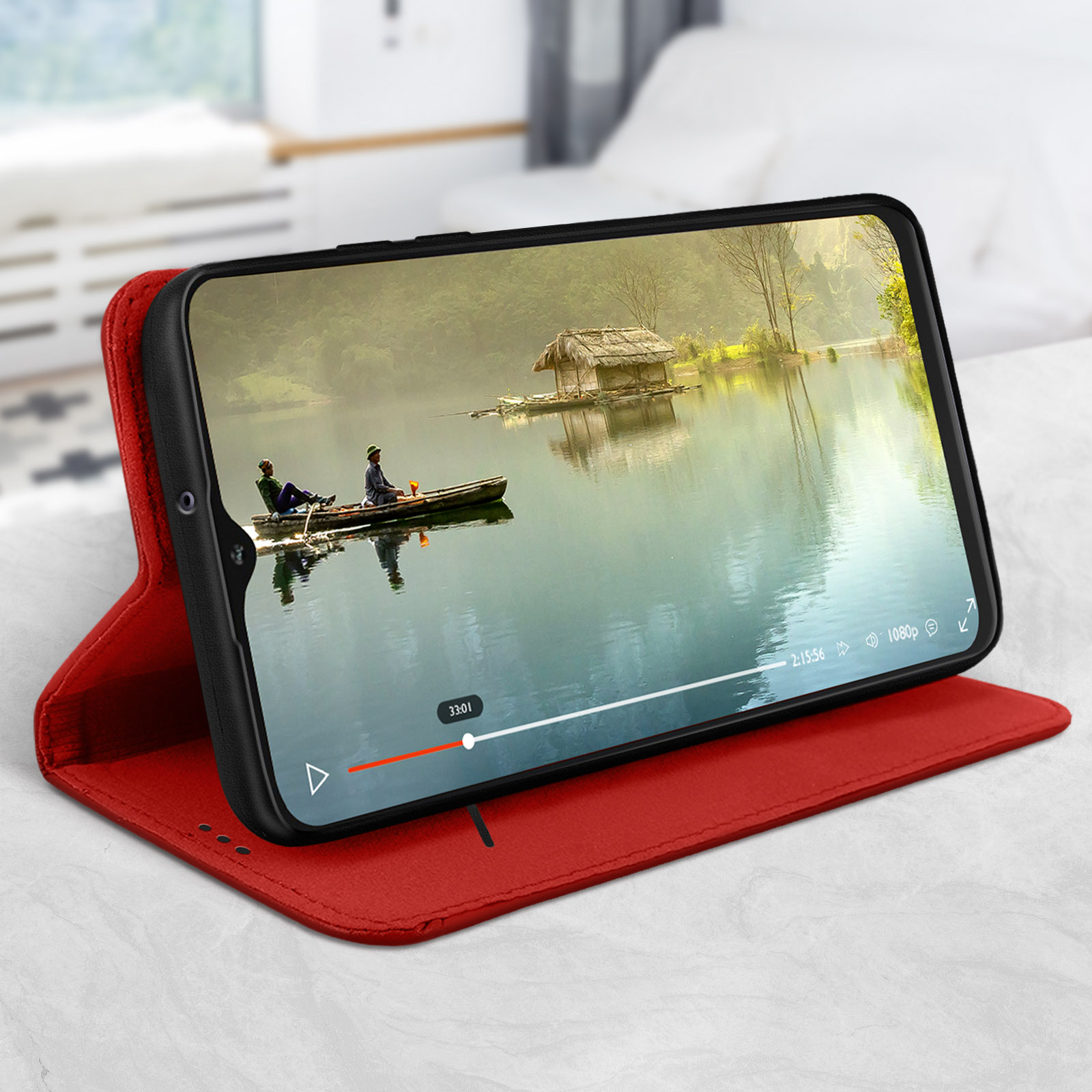 Telefono in custodia rossa, riproduce video di lago e barca. Letto e finestra sullo sfondo.