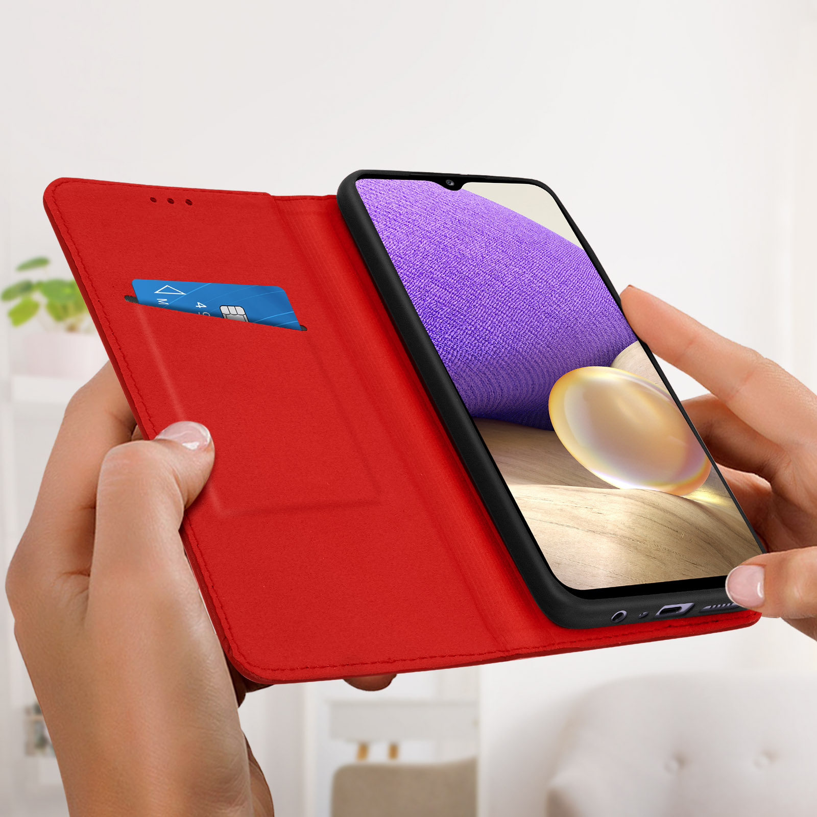 Una custodia rossa per telefono è aperta, rivelando una carta di credito e uno smartphone con un'immagine.