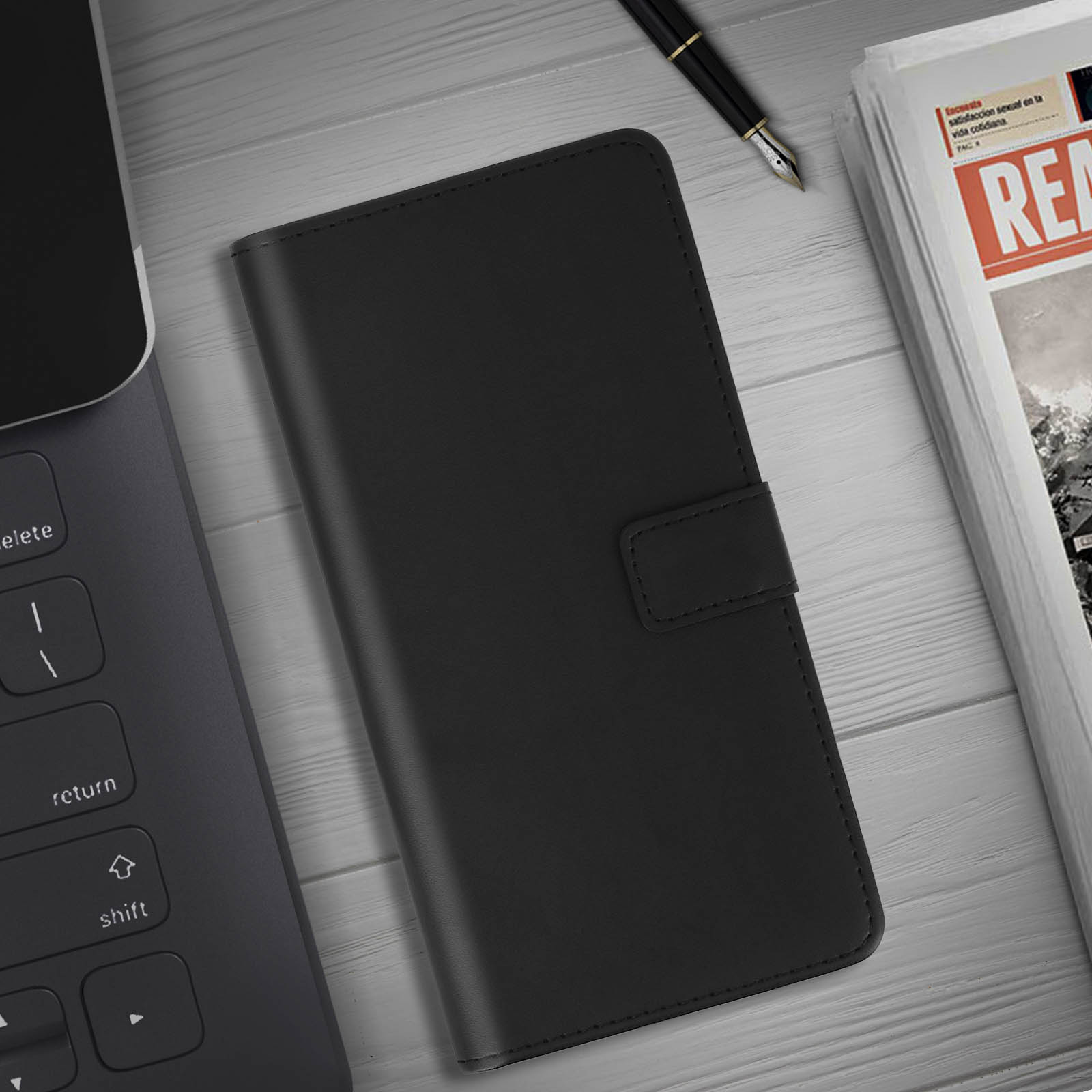 Coque de téléphone noire sur une table en bois avec clavier d'ordinateur et stylo.