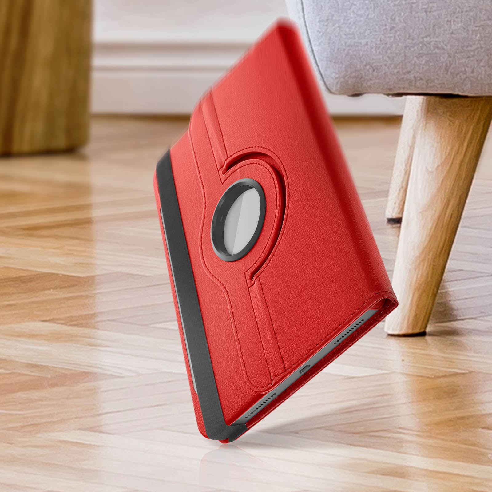 Custodia per tablet rossa, aperta, angolata. Tablet all'interno. Lo sfondo è un pavimento in legno.