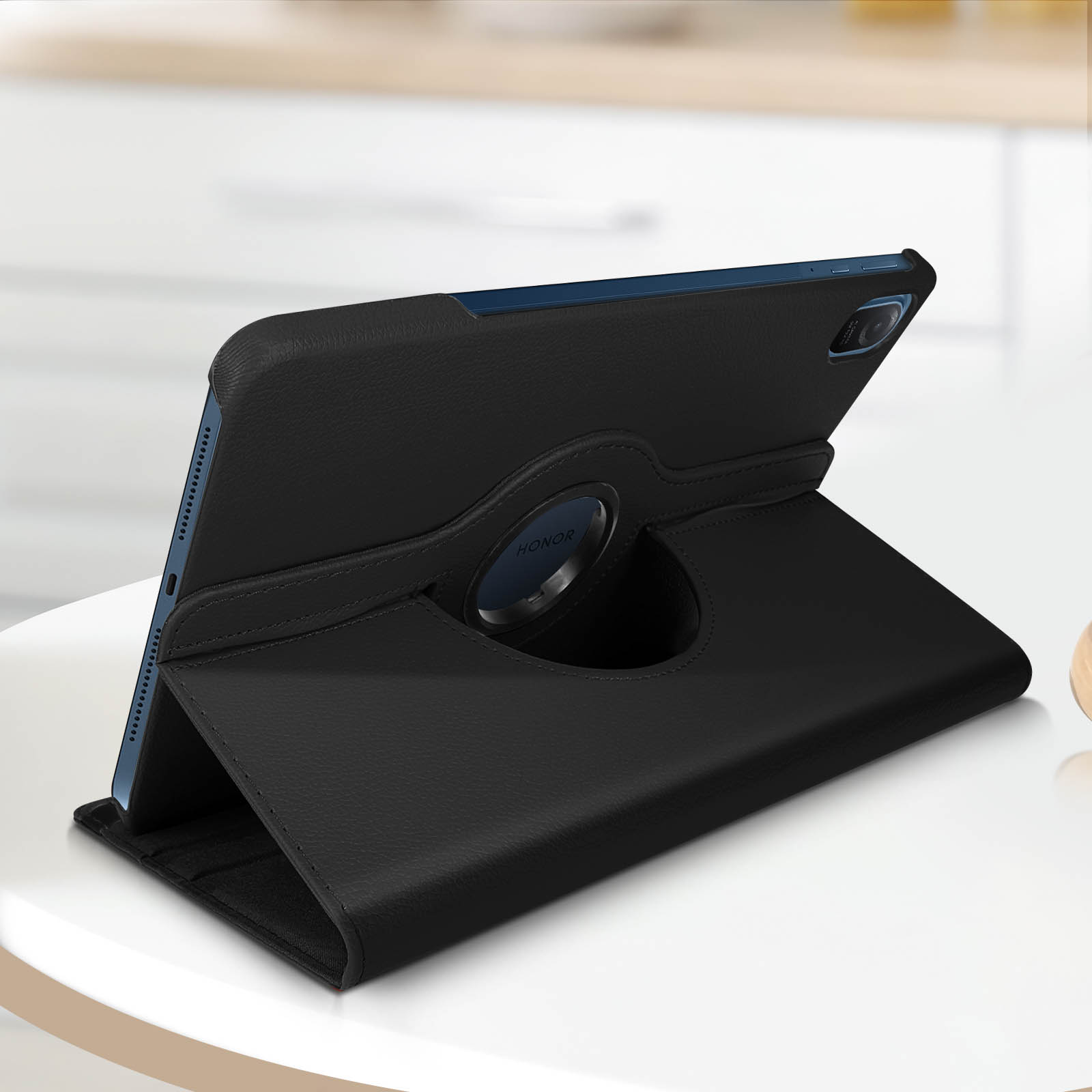 Custodia nera per tablet su un tavolo bianco. Angolata, con logo HONOR. Sfondo sfocato.