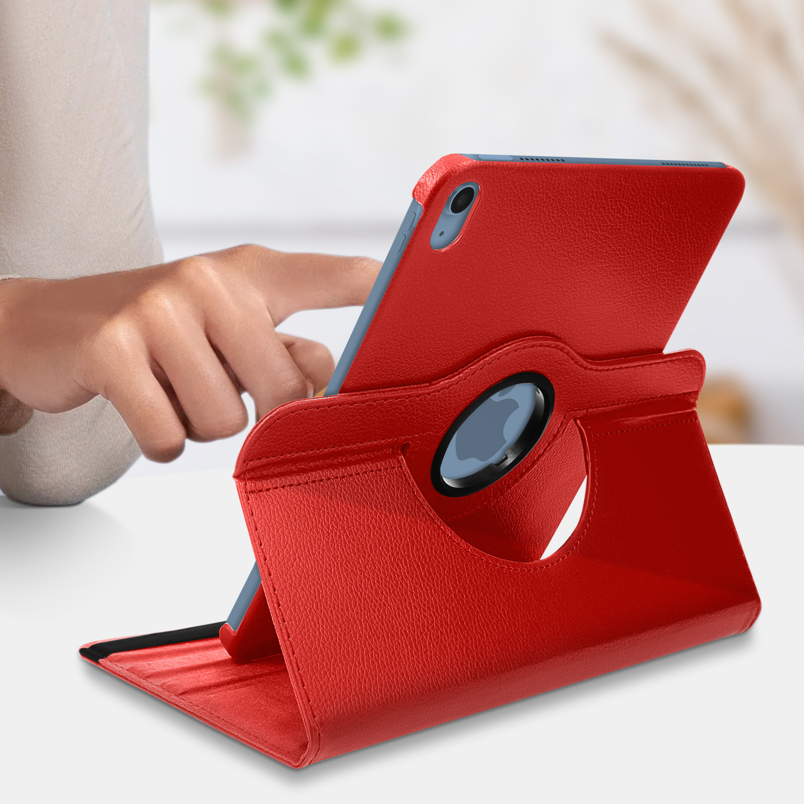 Rote Tablethülle mit Tablet. Die Hülle ist gefaltet und eine Hand liegt auf dem Tisch.
