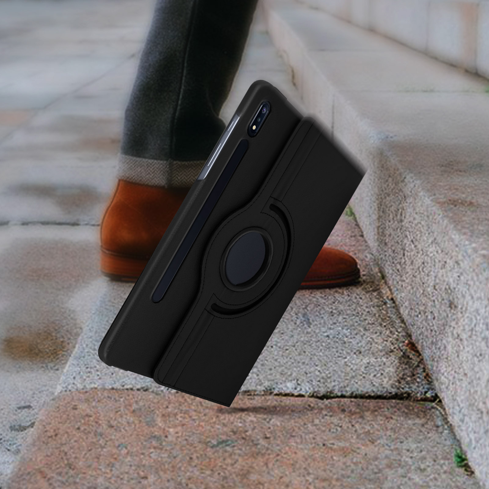 Un telefono nero in una custodia è su una scala. Una persona con scarpe marroni è sullo sfondo.