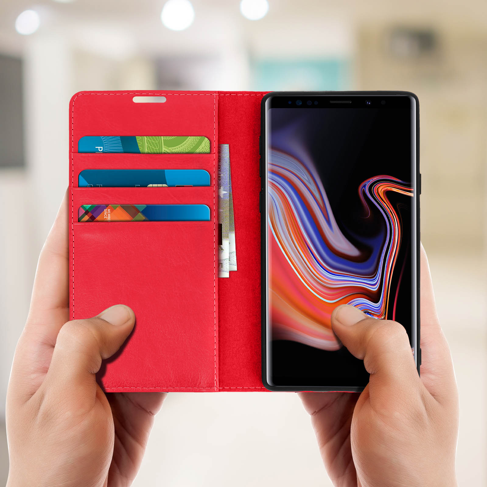 Mani che tengono una custodia rossa per telefono con carte e un telefono.