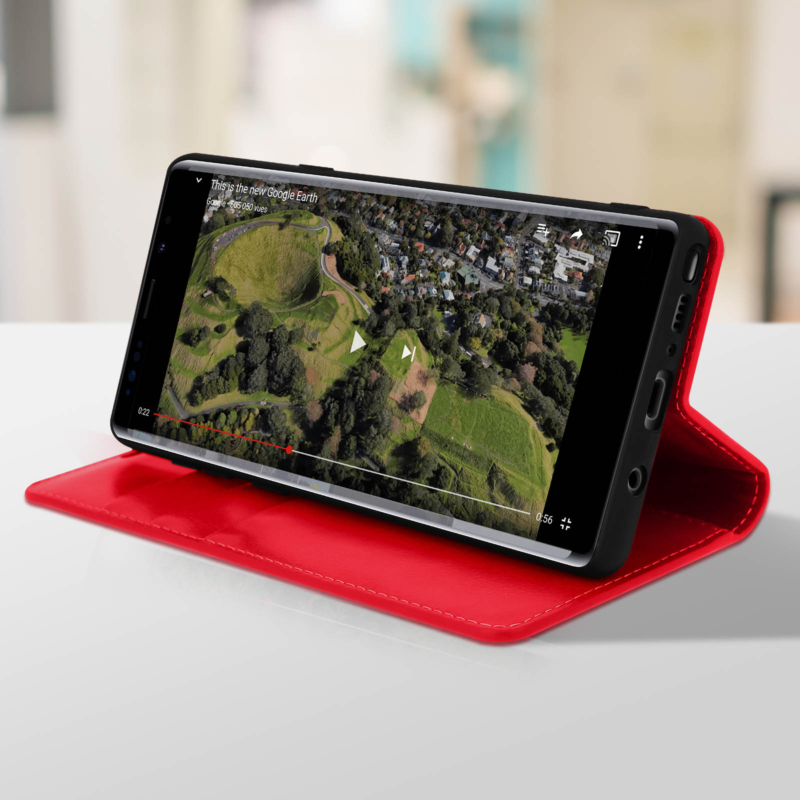 Telefono in custodia rossa mostra Google Earth. La custodia è su un tavolo bianco, sfondo sfocato.