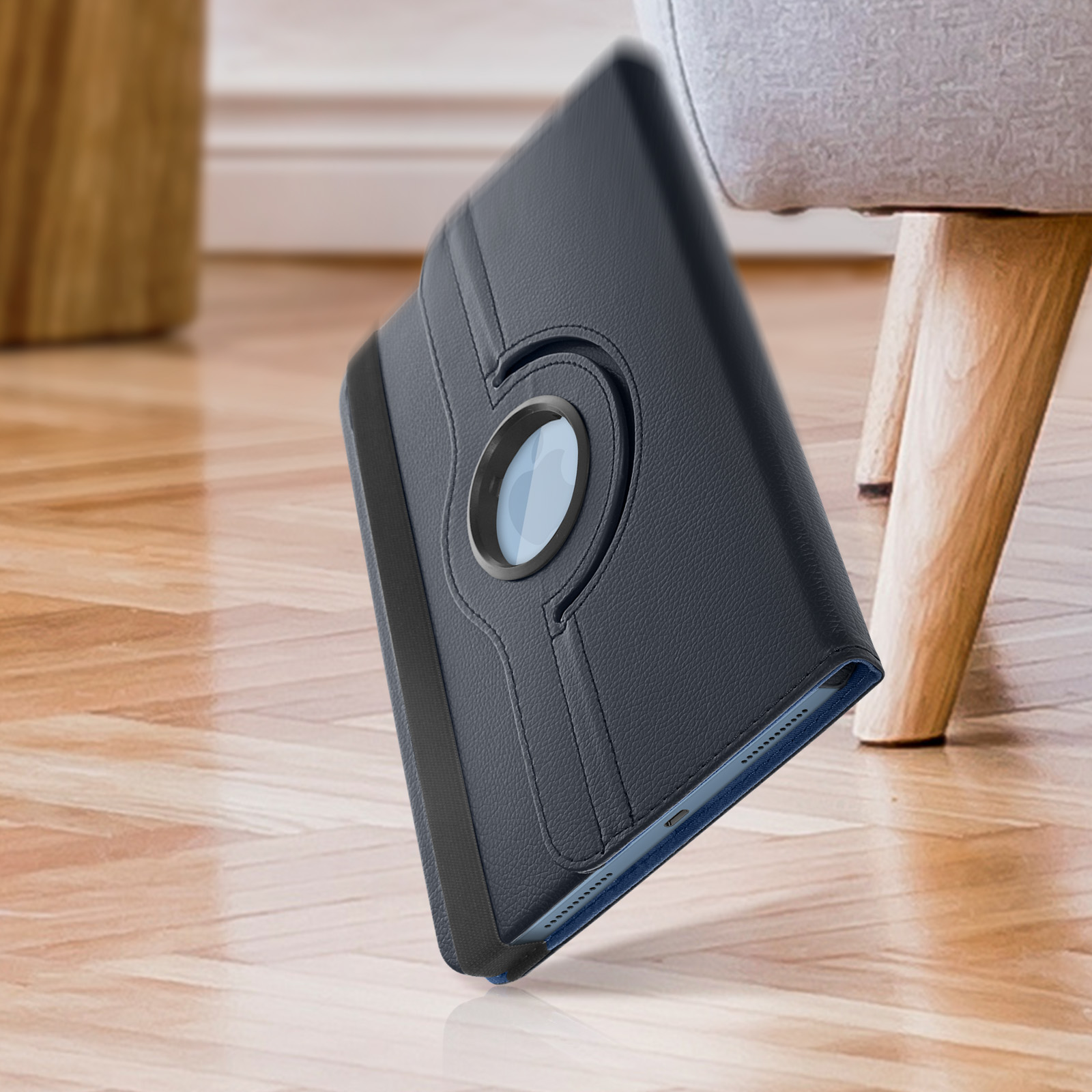 Una custodia per tablet, nera, su un pavimento di legno. Ruota, mostrando uno schermo blu.