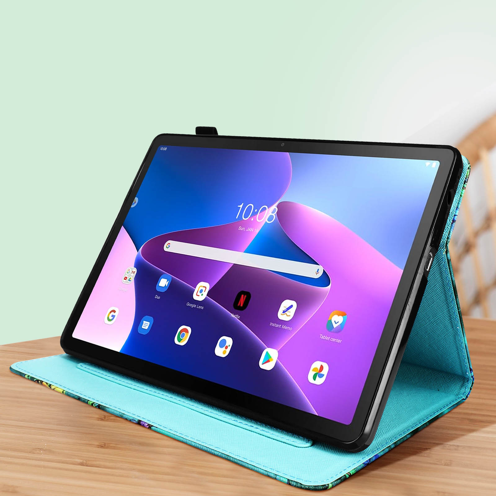 Tablet in una custodia, su un tavolo di legno. Parete verde sullo sfondo. Ora 10:08 sul display.
