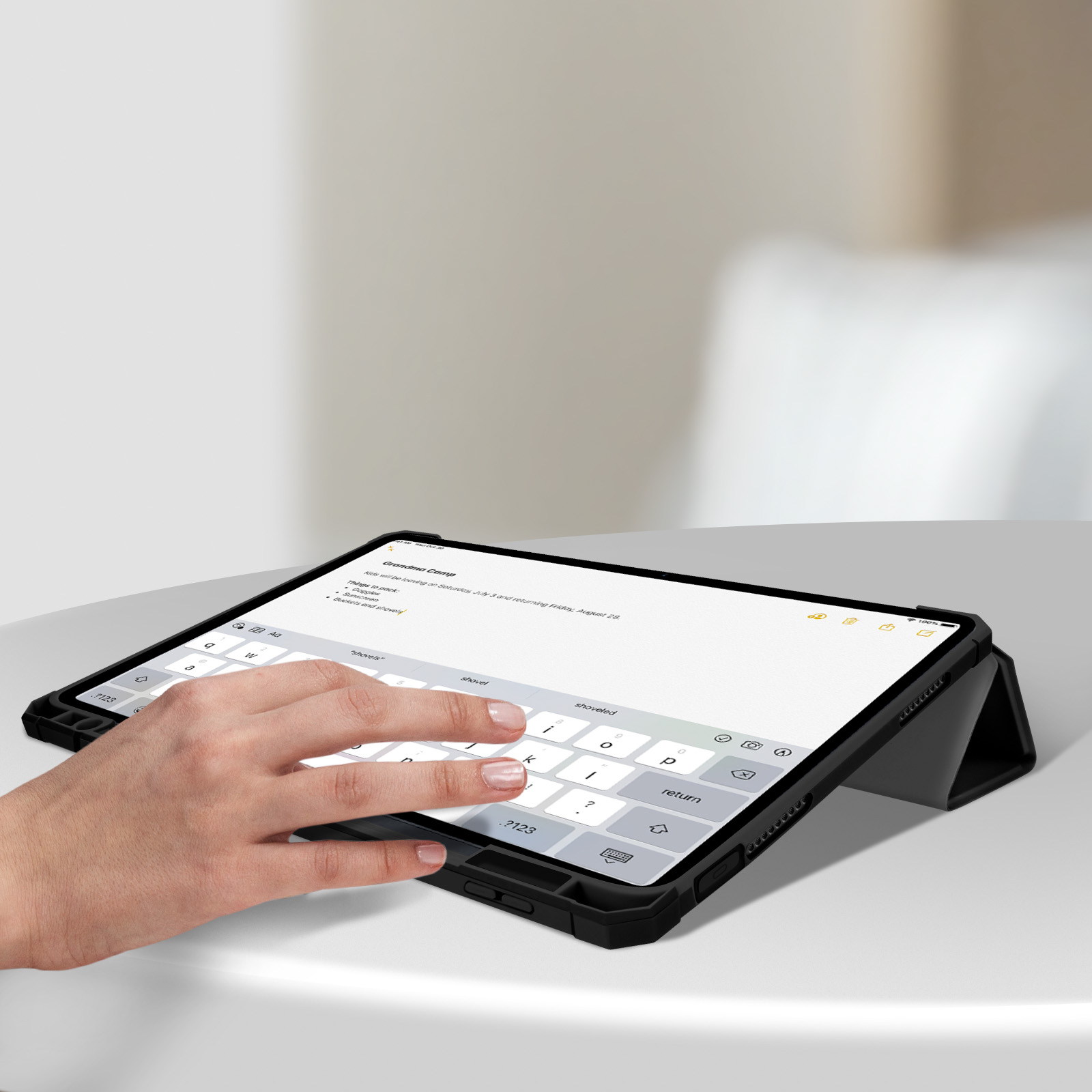 Persona che digita su tablet con custodia per tastiera su tavolo bianco.