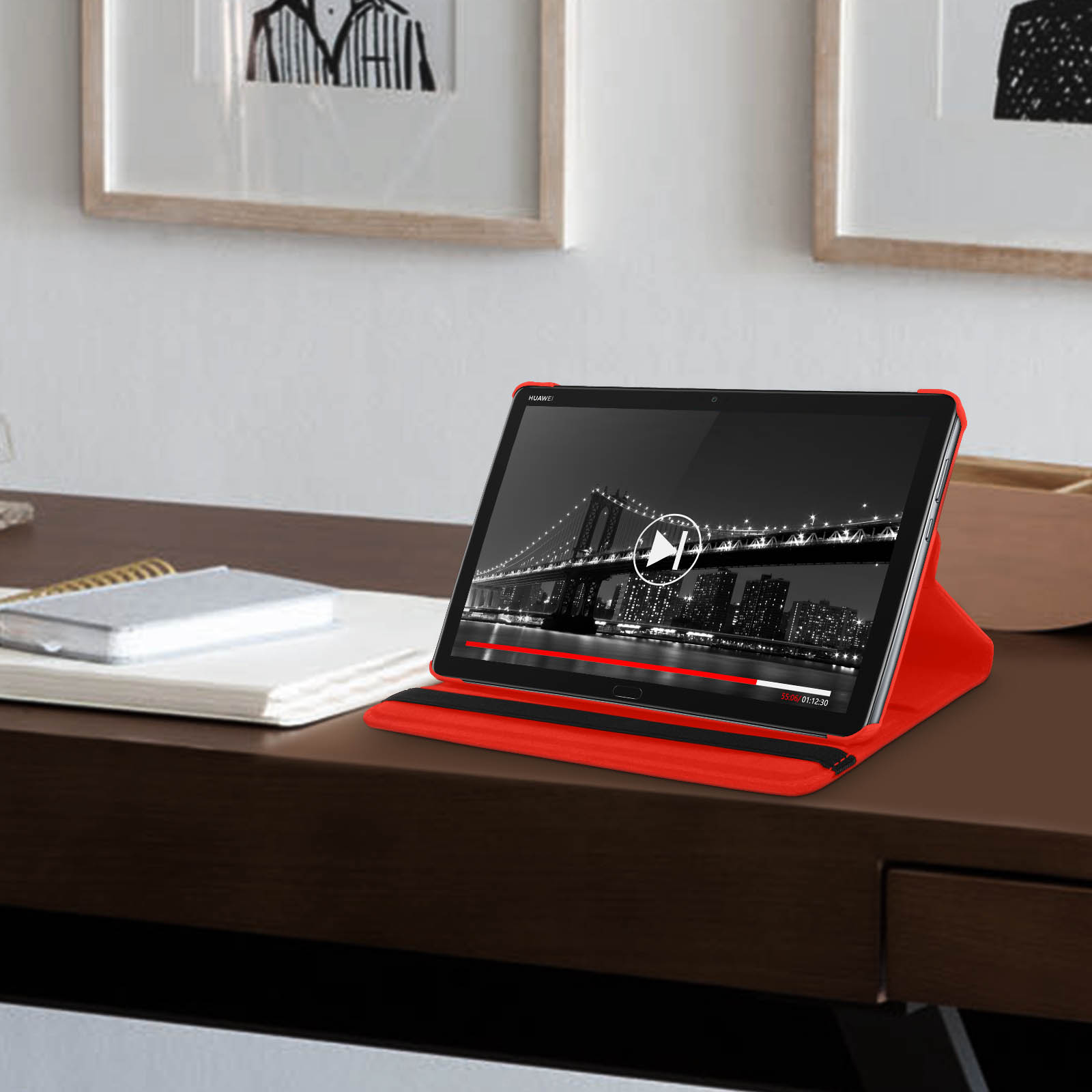 Tablet in custodia rossa su scrivania. Schermo mostra video con panorama urbano.