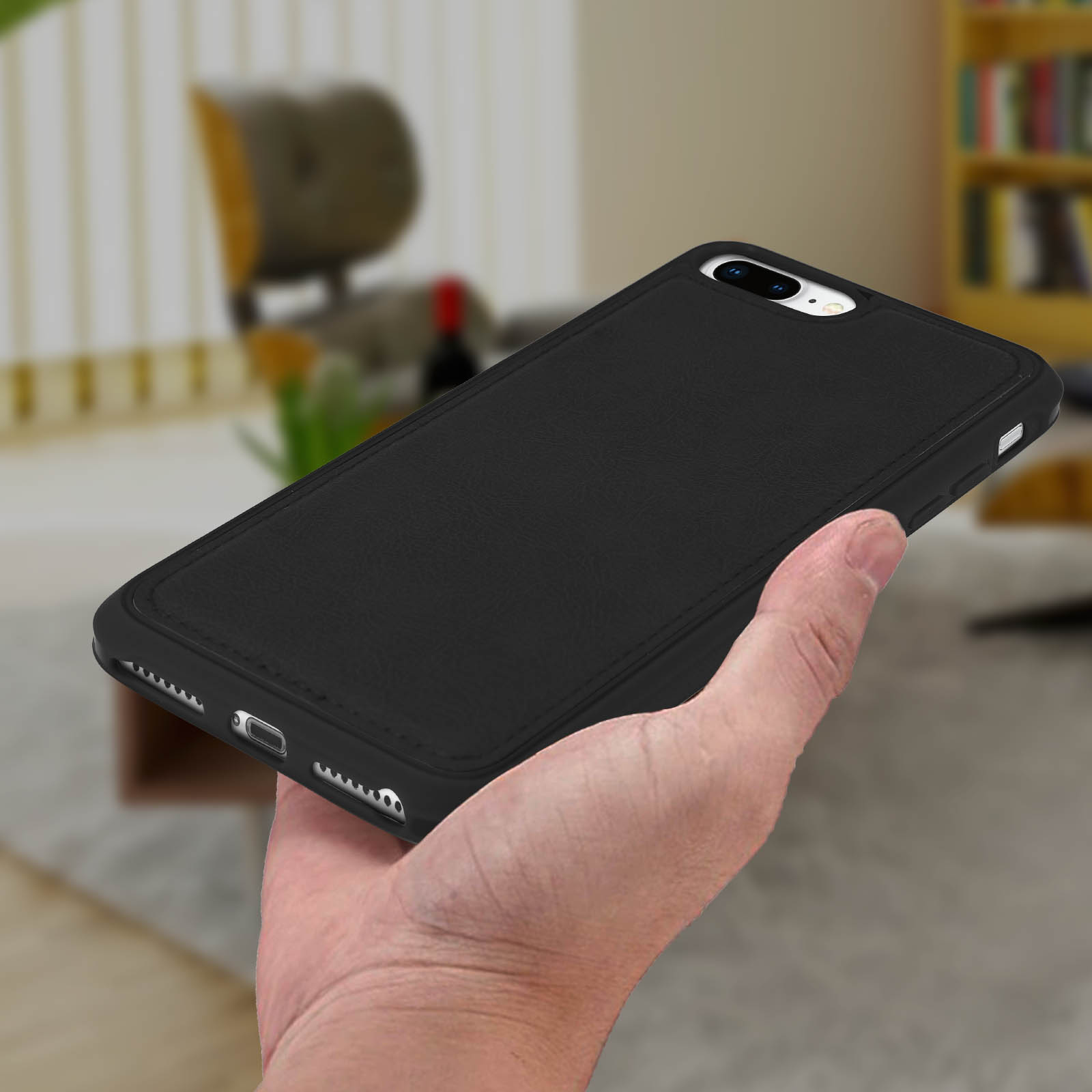 Hand hält ein schwarzes Telefon in einer schwarzen Hülle. Der Hintergrund ist unscharf mit Schreibtisch und Stuhl.