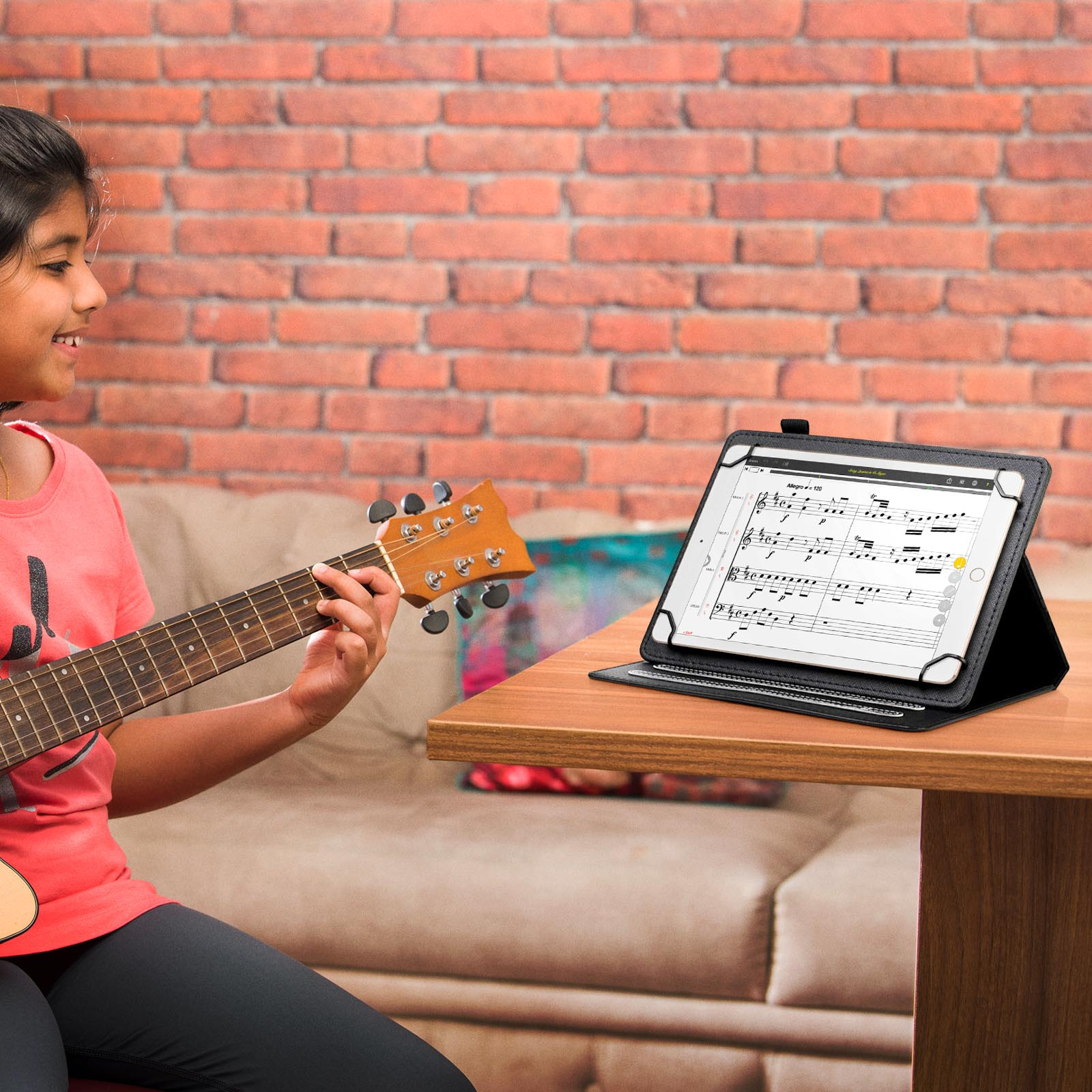 Ragazza con chitarra guarda un tablet con note musicali su una scrivania.