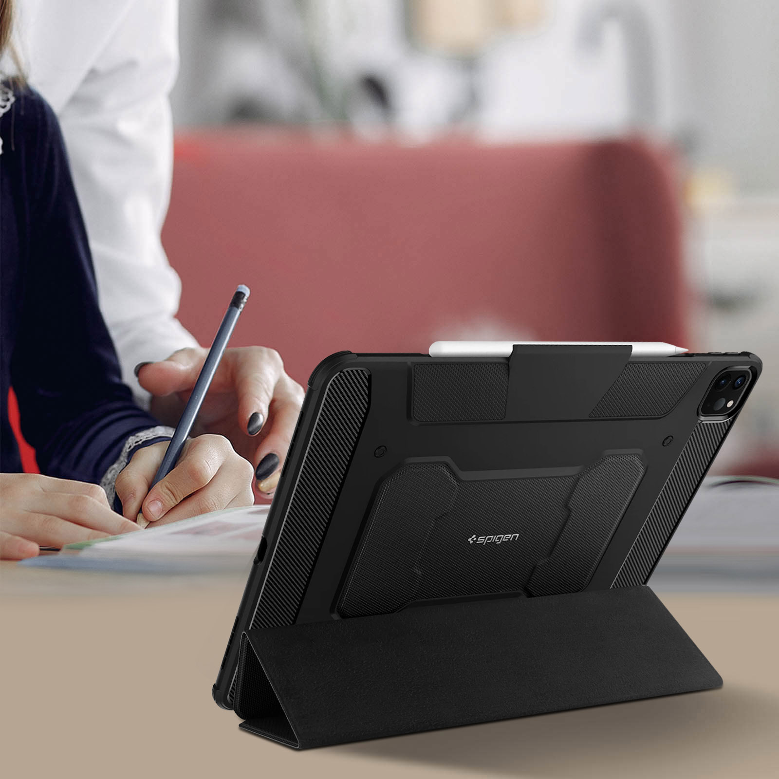 Tablet in una custodia nera con una persona che scrive. La matita è tenuta sul tablet.