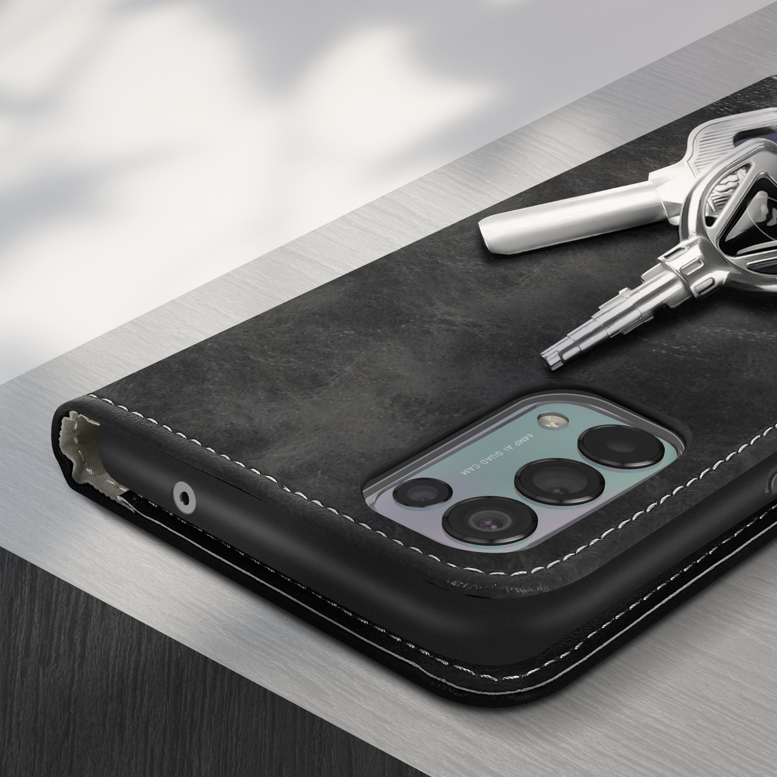 Une coque de téléphone noire avec un téléphone à l'intérieur. Des clés sont placées à côté de la coque.