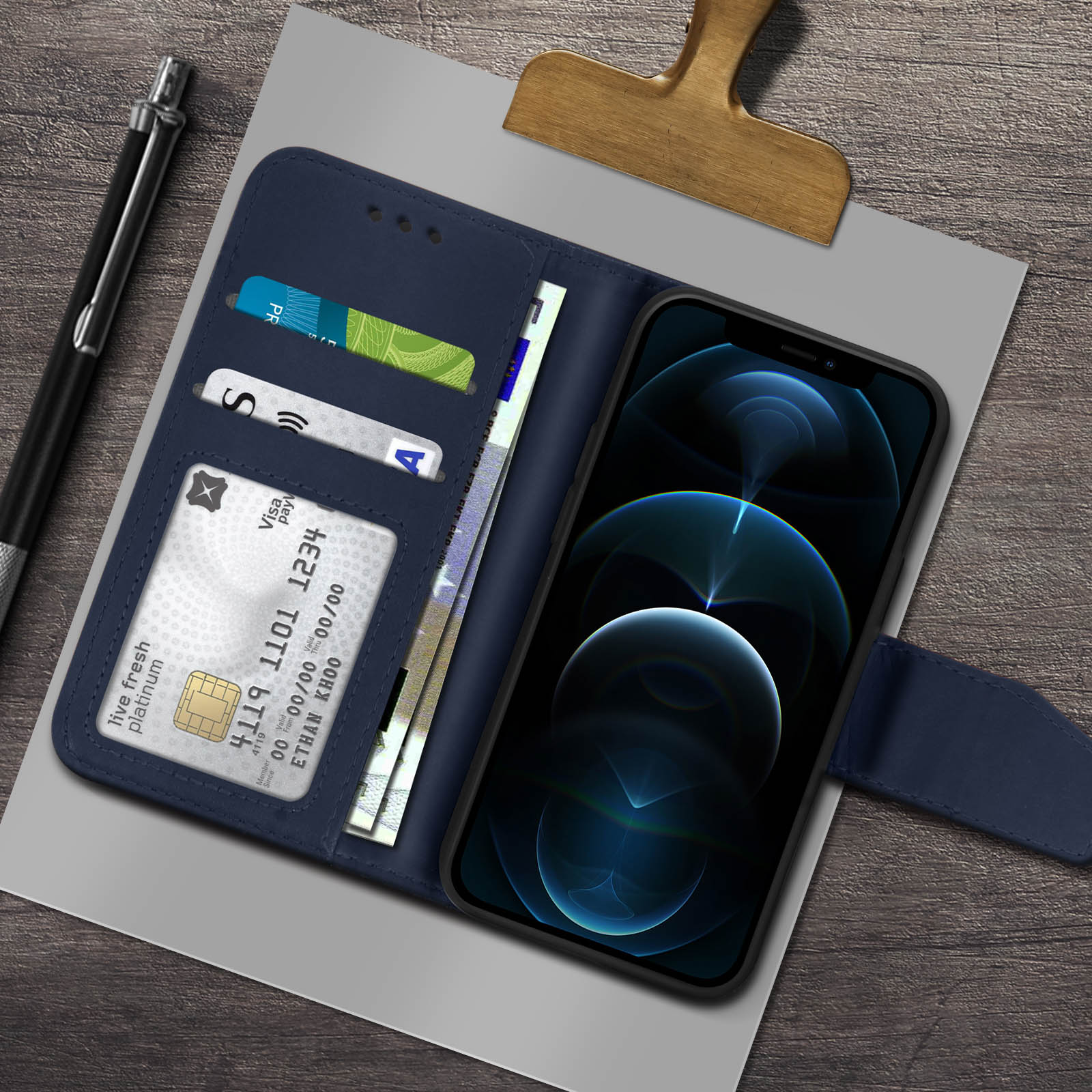 Blauwe telefoonhoes open met kaarten, contanten en telefoon erin. Pen en papier op tafel.