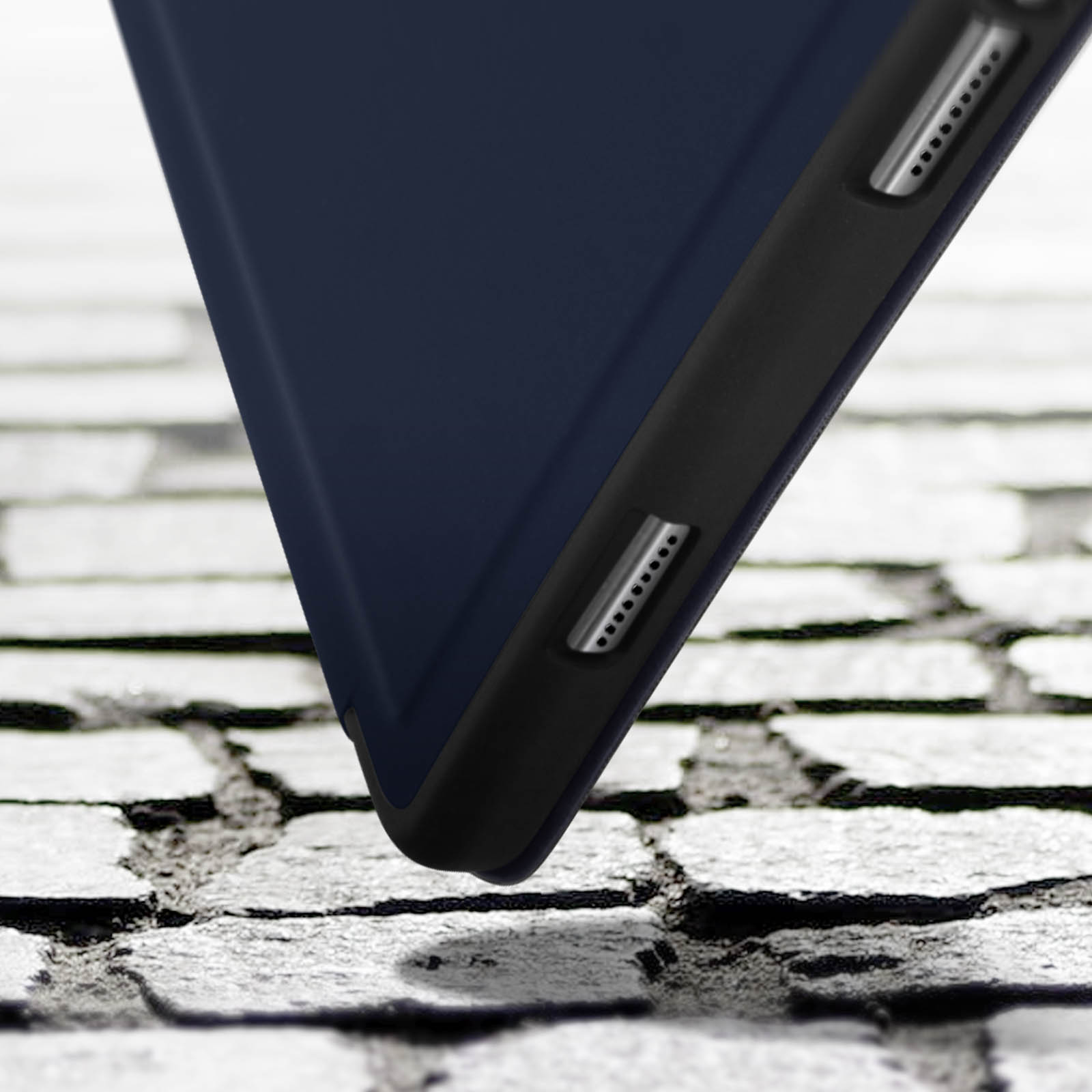Primo piano di una custodia blu per tablet su una superficie in mattoni. Mostra il bordo.