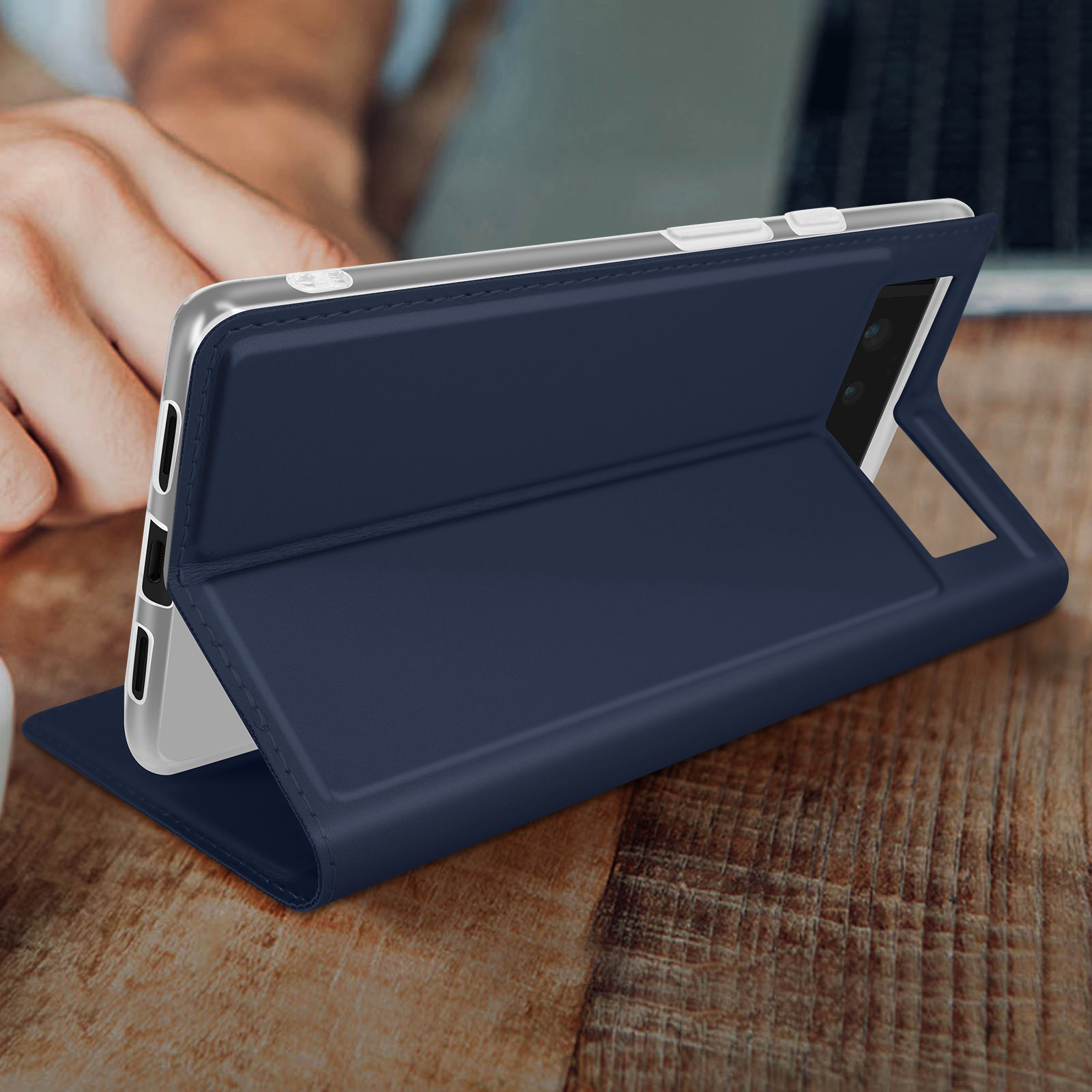 Ein Telefon in einer blauen Hülle liegt auf einem Holztisch, aufgeklappt.