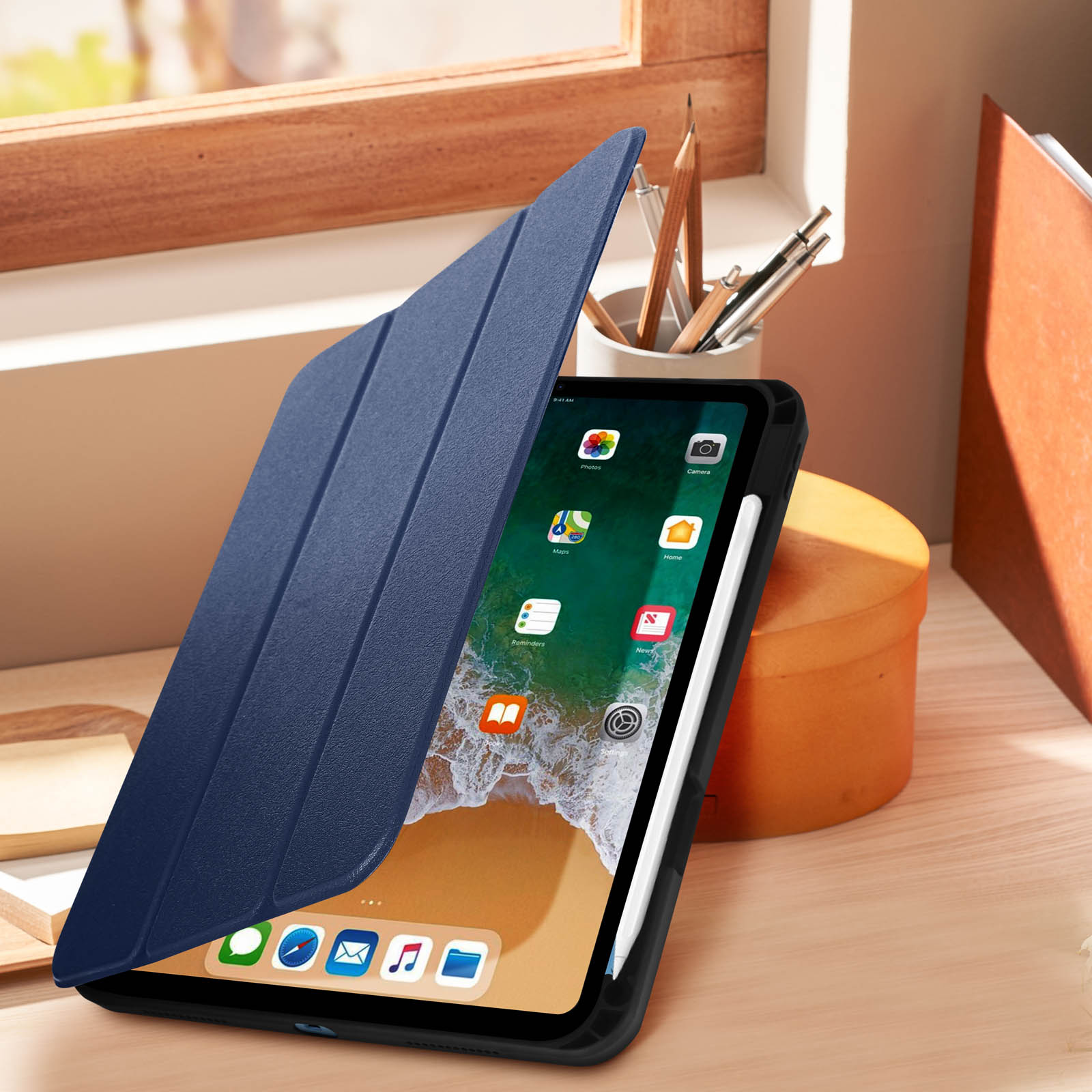 Tablet con custodia blu aperta, stilo bianco e matite su un tavolo di legno.