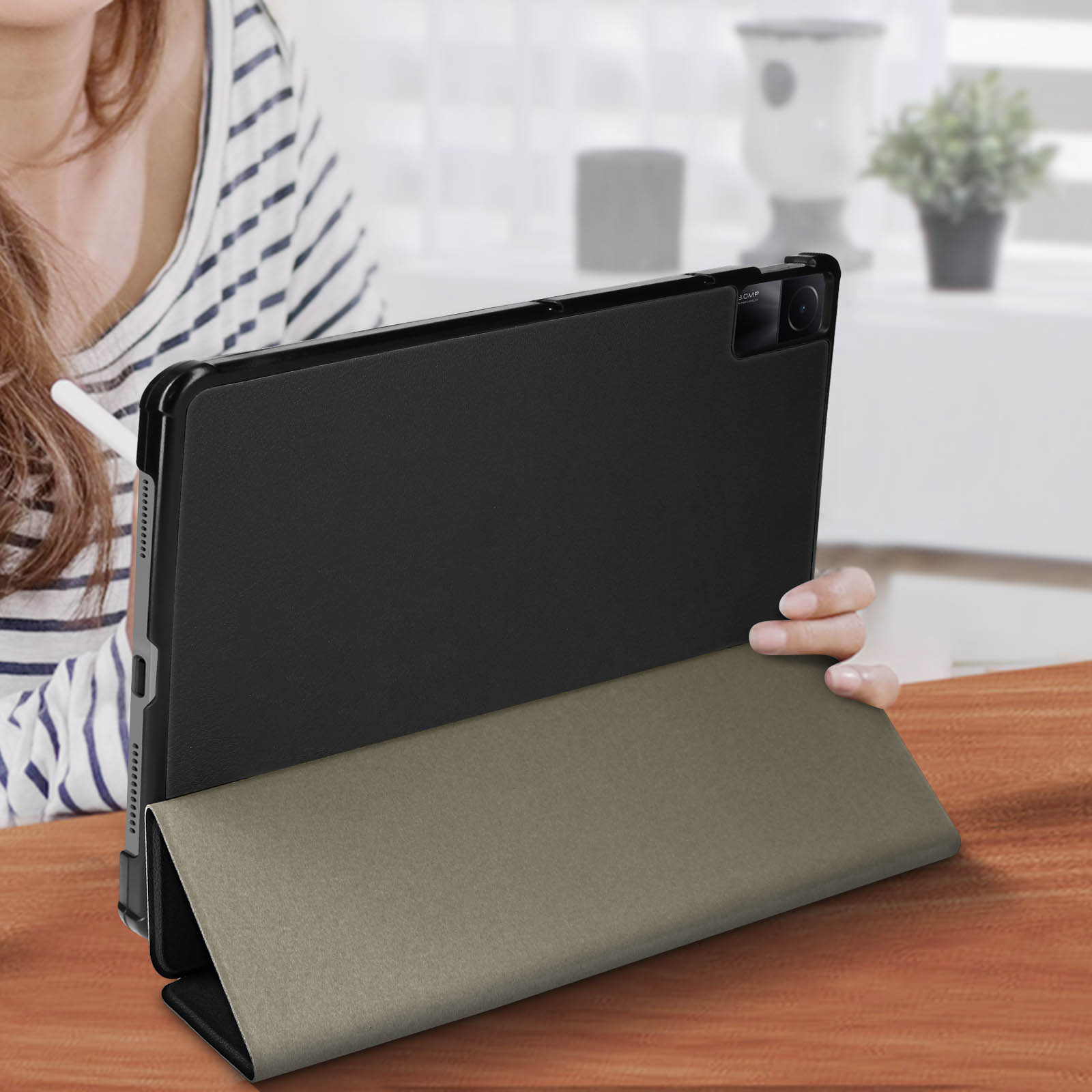 Tablet in una custodia su un tavolo di legno. Le mani di una donna sullo sfondo.