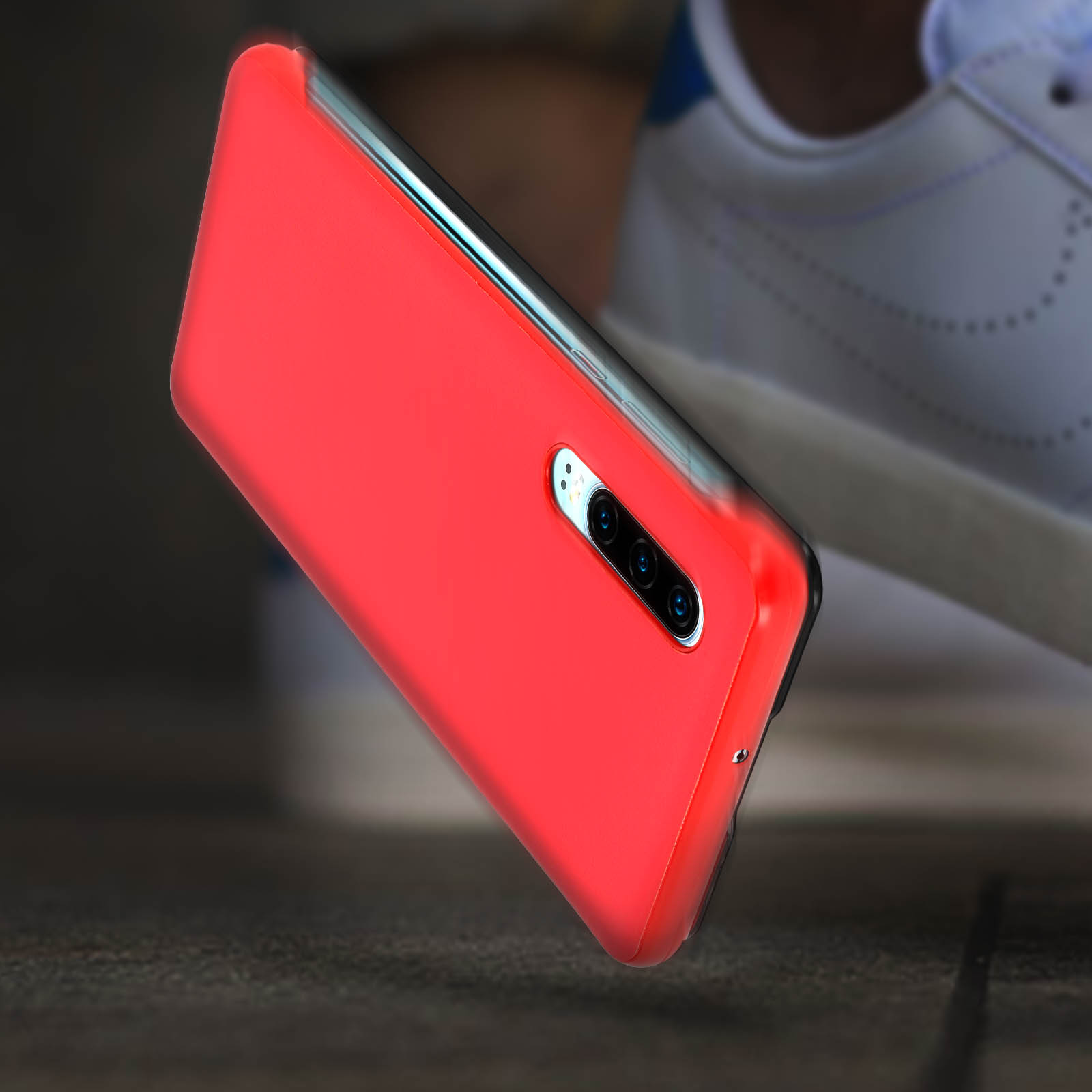 Rote Telefonhülle, mit Kameradetails. Hintergrund sind weiße Turnschuhe auf Holz.
