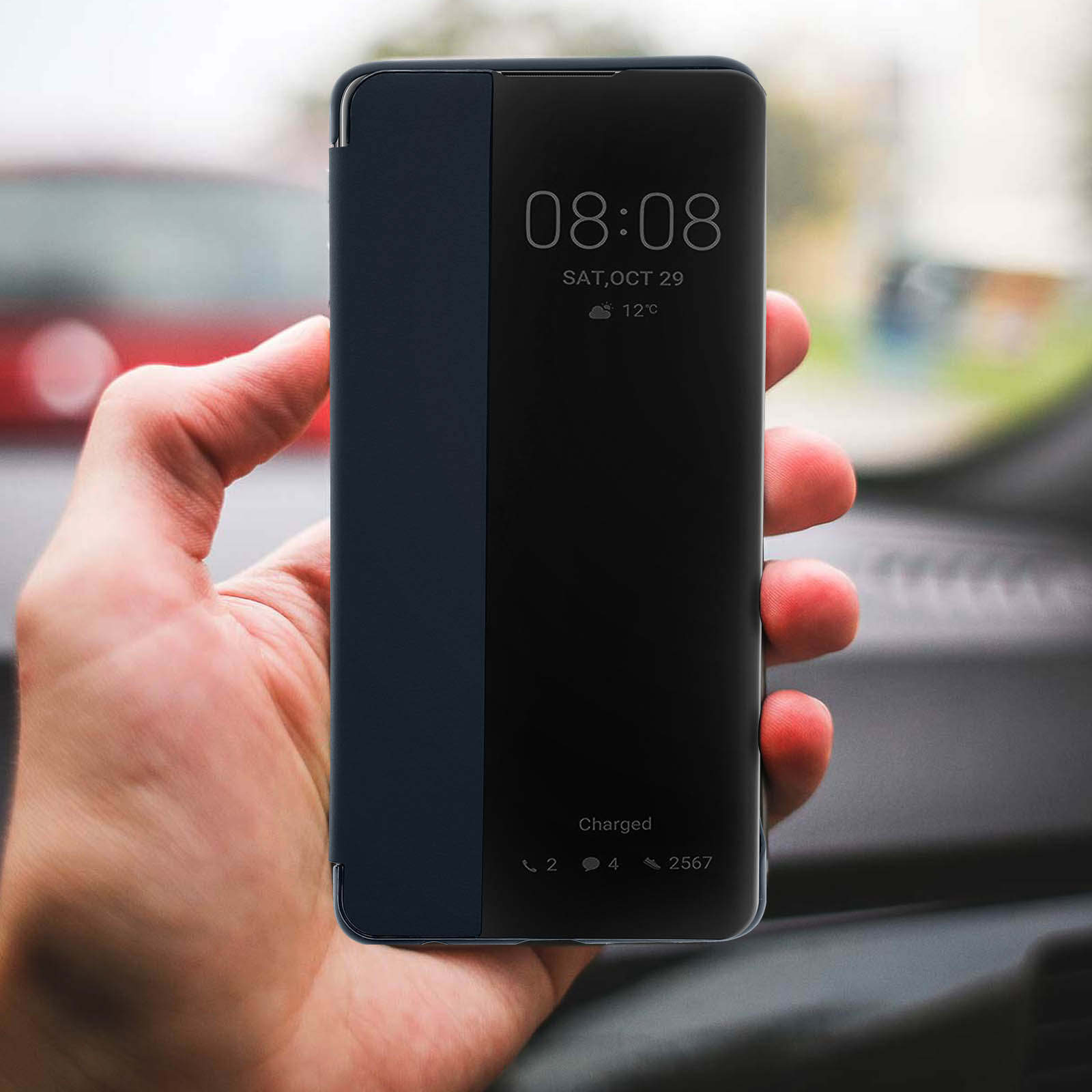 Mano che tiene un telefono con una cover blu scuro che mostra l'ora, la data e 'caricato'.