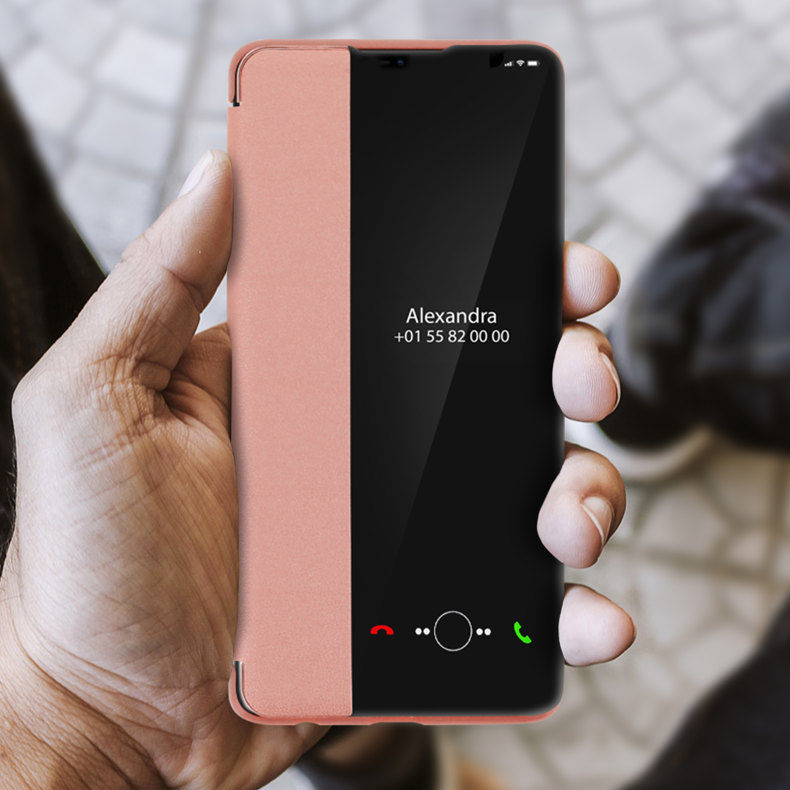 Eine Hand hält ein Telefon. Telefon zeigt einen Anrufbildschirm mit Namen und Nummer. Pfirsich- und schwarzes Gehäuse.