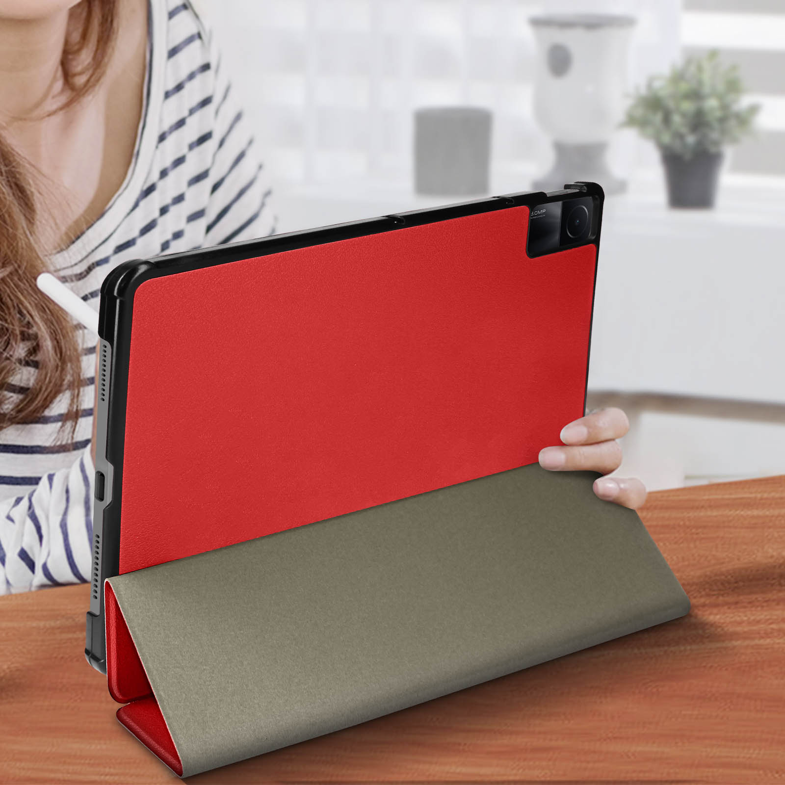 Un tablet in una custodia rossa, tenuto in mano, con uno stilo.