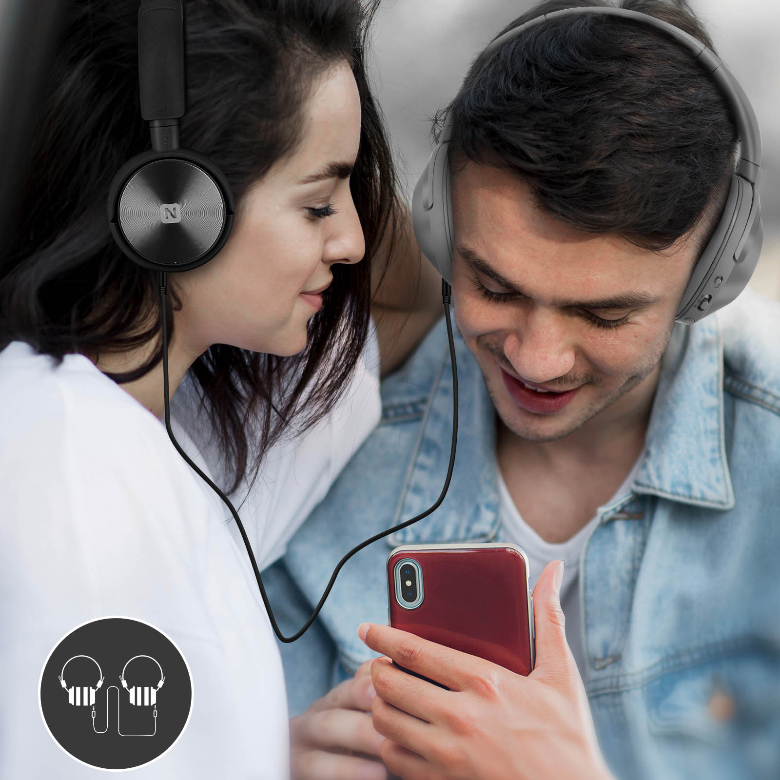 Zwei Personen teilen Musik über Kopfhörer, die mit einem Telefon verbunden sind. Das Telefon ist rot.