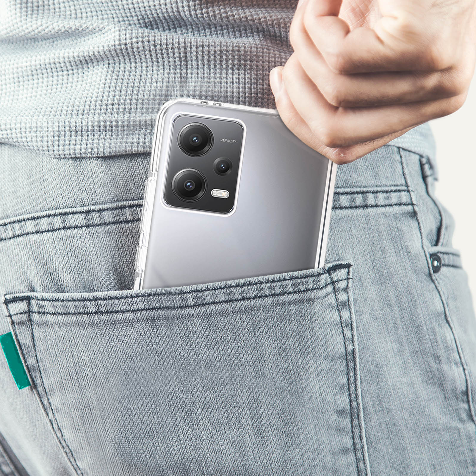 Un telefono in una custodia trasparente in una tasca dei jeans. Il telefono è argento.